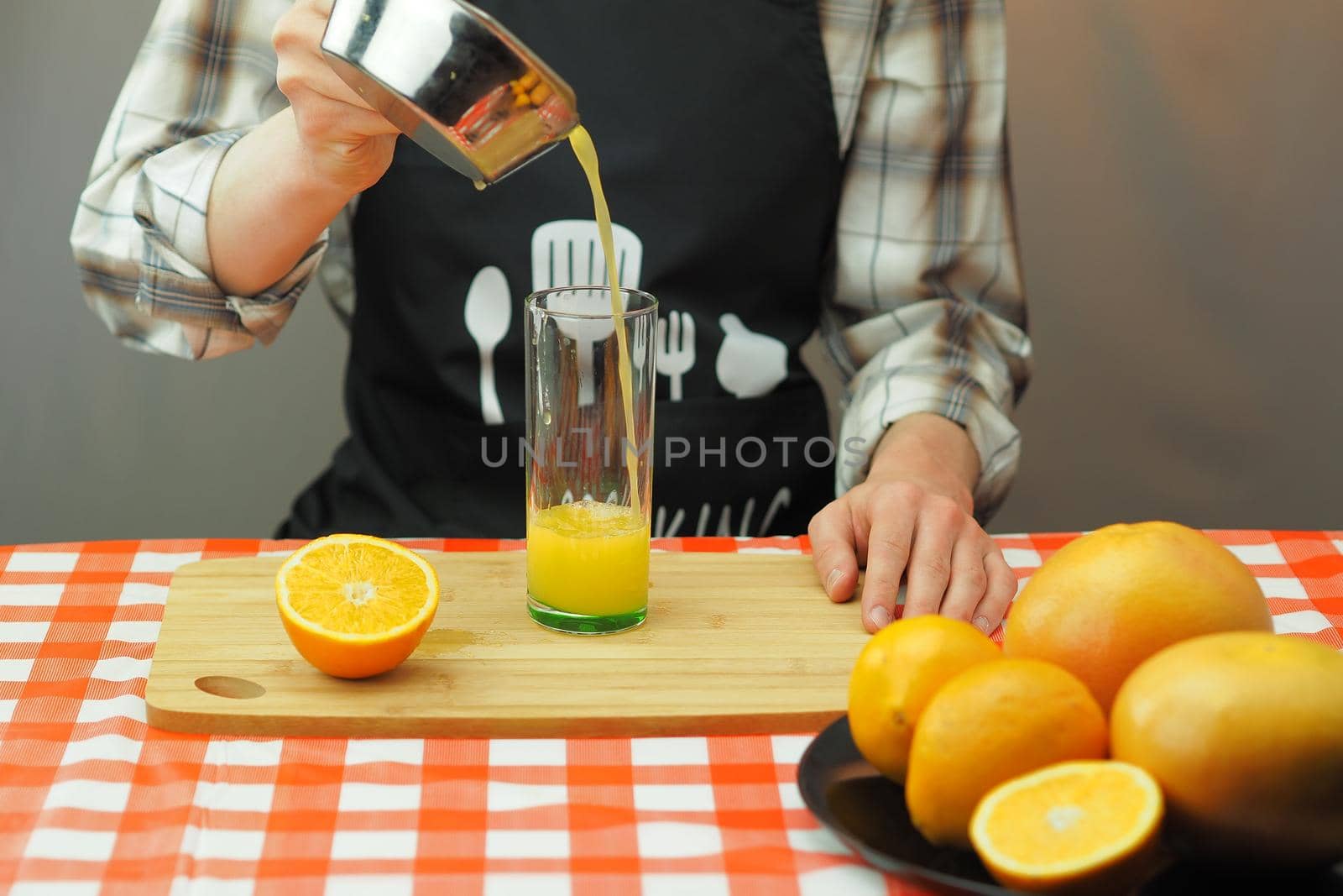 A young man pours freshly squeezed citrus juice into a transparent glass. by Olga26