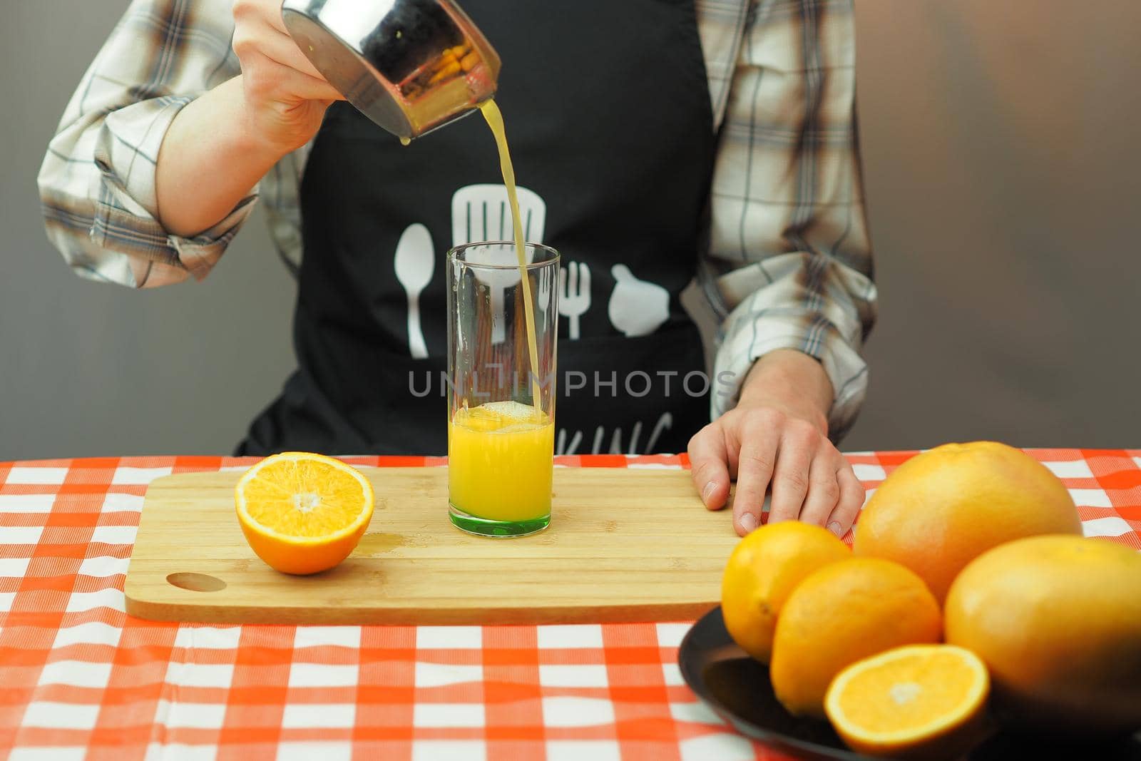 A young man pours freshly squeezed citrus juice into a transparent glass. by Olga26