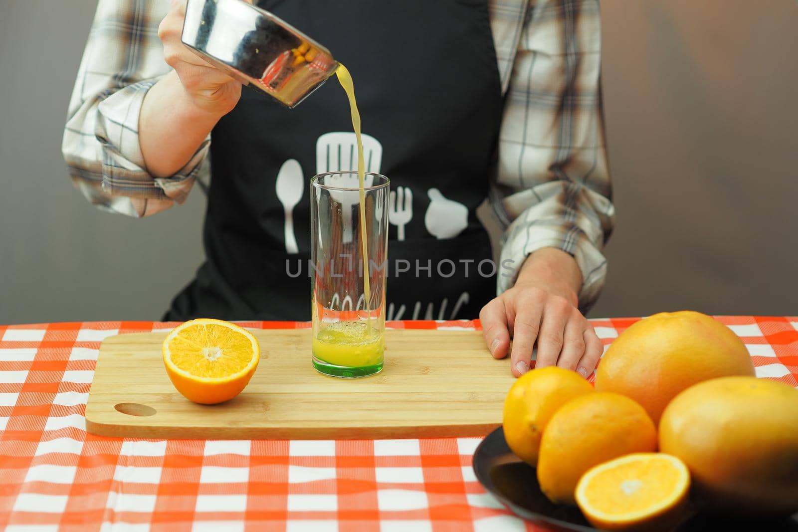 A young man pours freshly squeezed citrus juice into a transparent glass. by Olga26