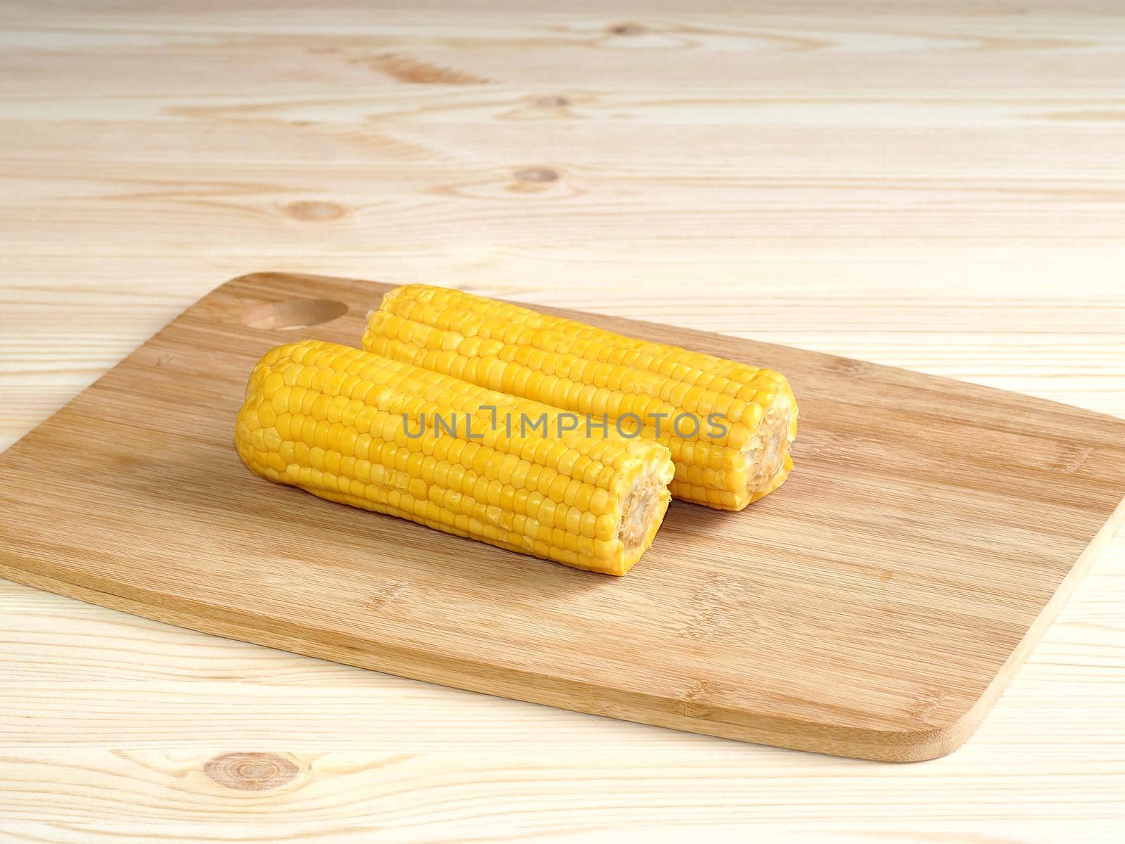 Boiled corn pob and sweet popcorn. Ears of cooked sweet corn on a wooden table scattered popcorn. Close-up, isolated. 