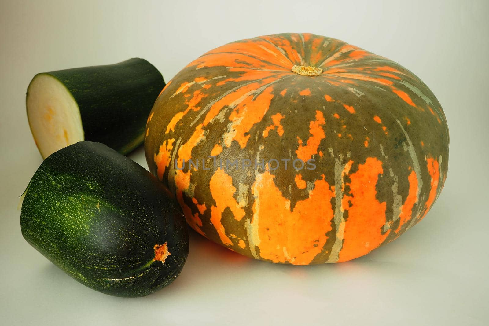 Ripe orange pumpkin and green ripe zucchini on a white background. by Olga26