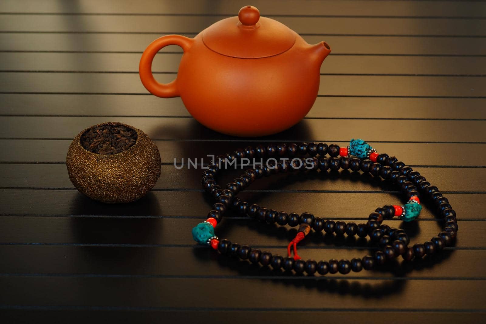 Chinese clay brown teapot for a tea ceremony with tea and edches on a black background. by Olga26