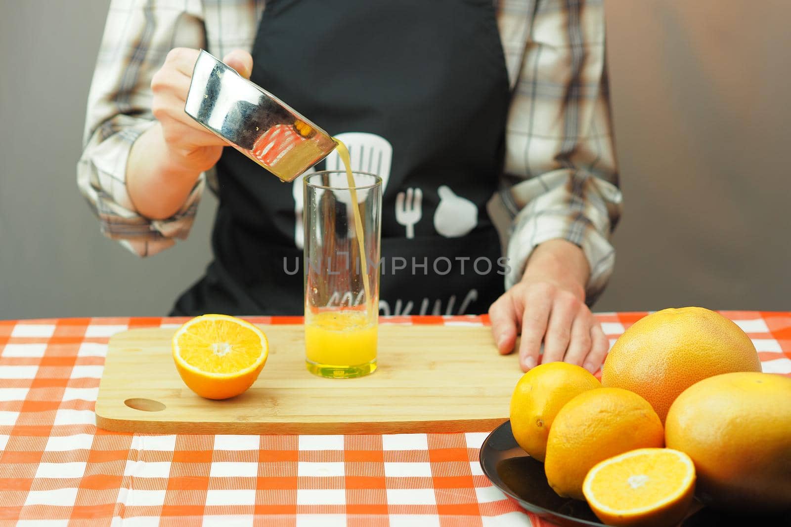 A young man pours freshly squeezed citrus juice into a transparent glass. High quality photo