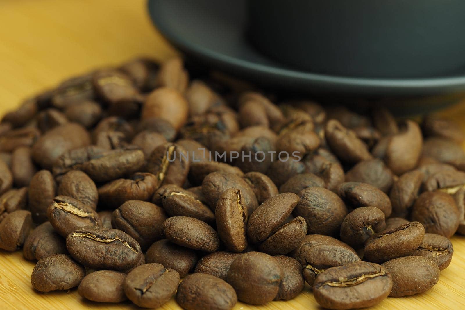 A beautiful background of natural coffee beans and a coffee cup in the background. High quality photo