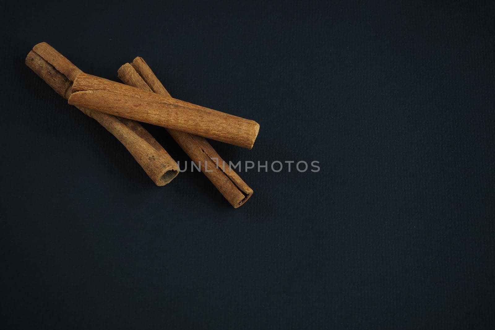 Ingredients and spices for pastries and drinks. Cinnamon sticks on a black background.