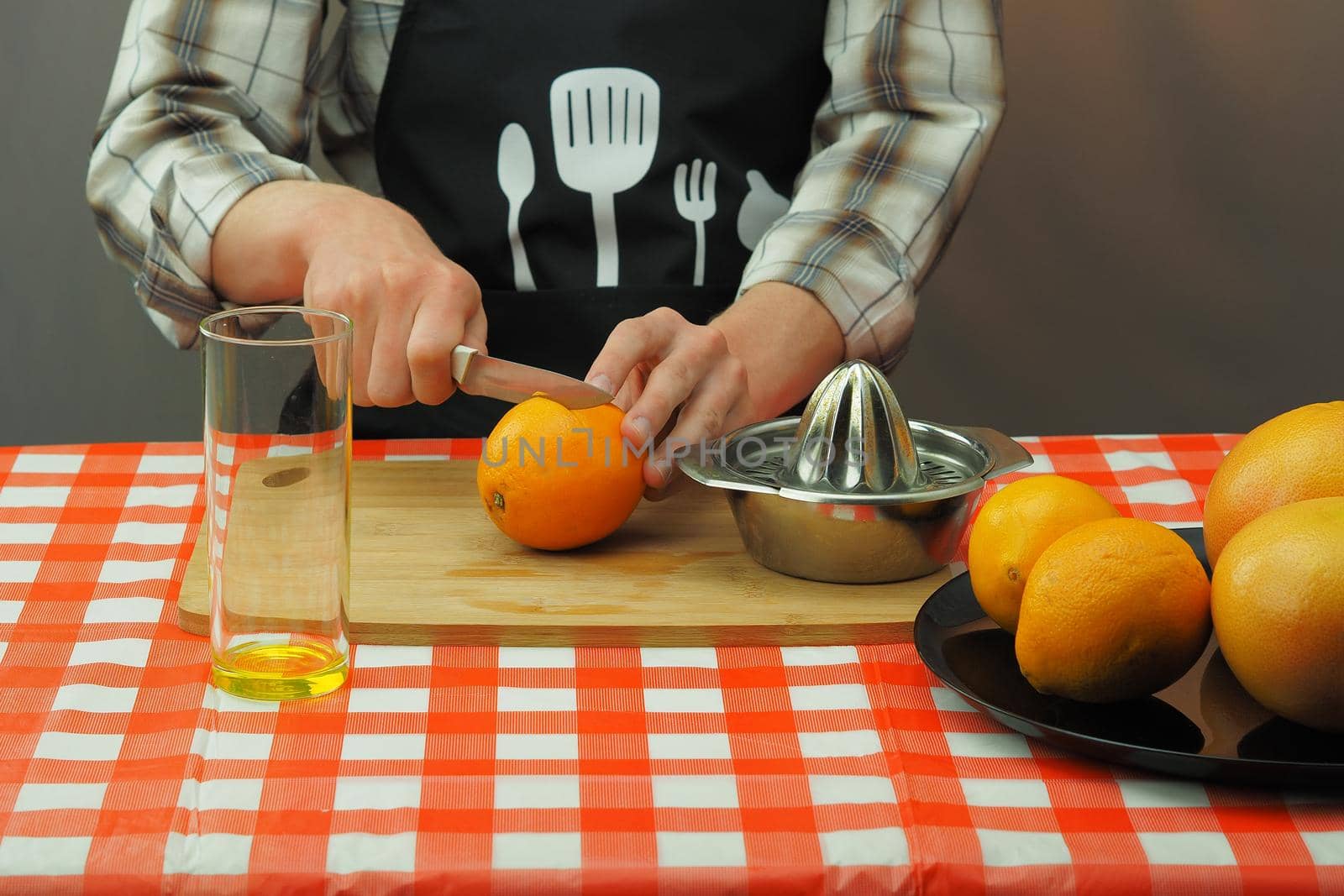 A young man in an apron makes freshly squeezed juice from orange and grapefruit. High quality photo