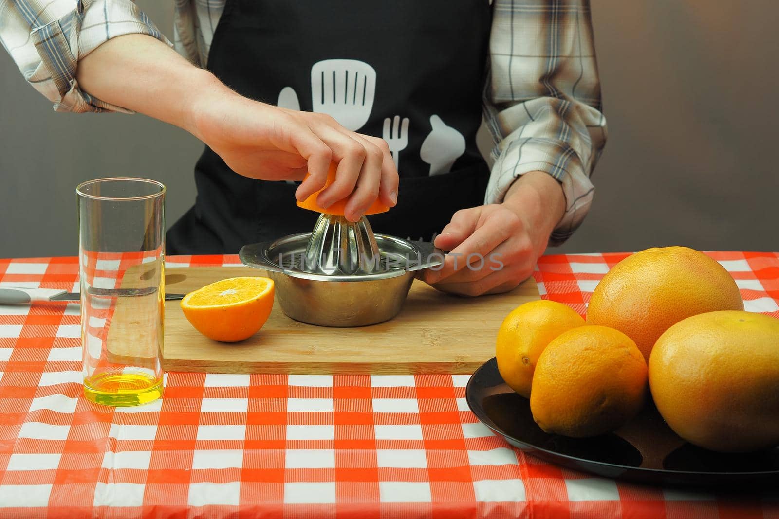 A young man in an apron makes freshly squeezed juice from orange and grapefruit. High quality photo