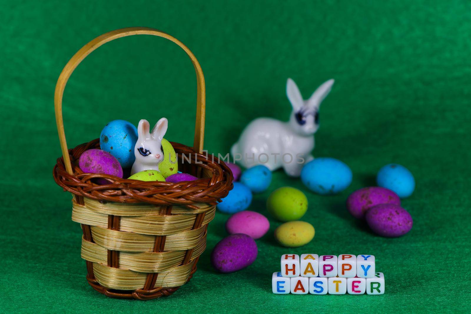 Happy Easter text beads with bunny in woven basket and colorful speckled eggs on green