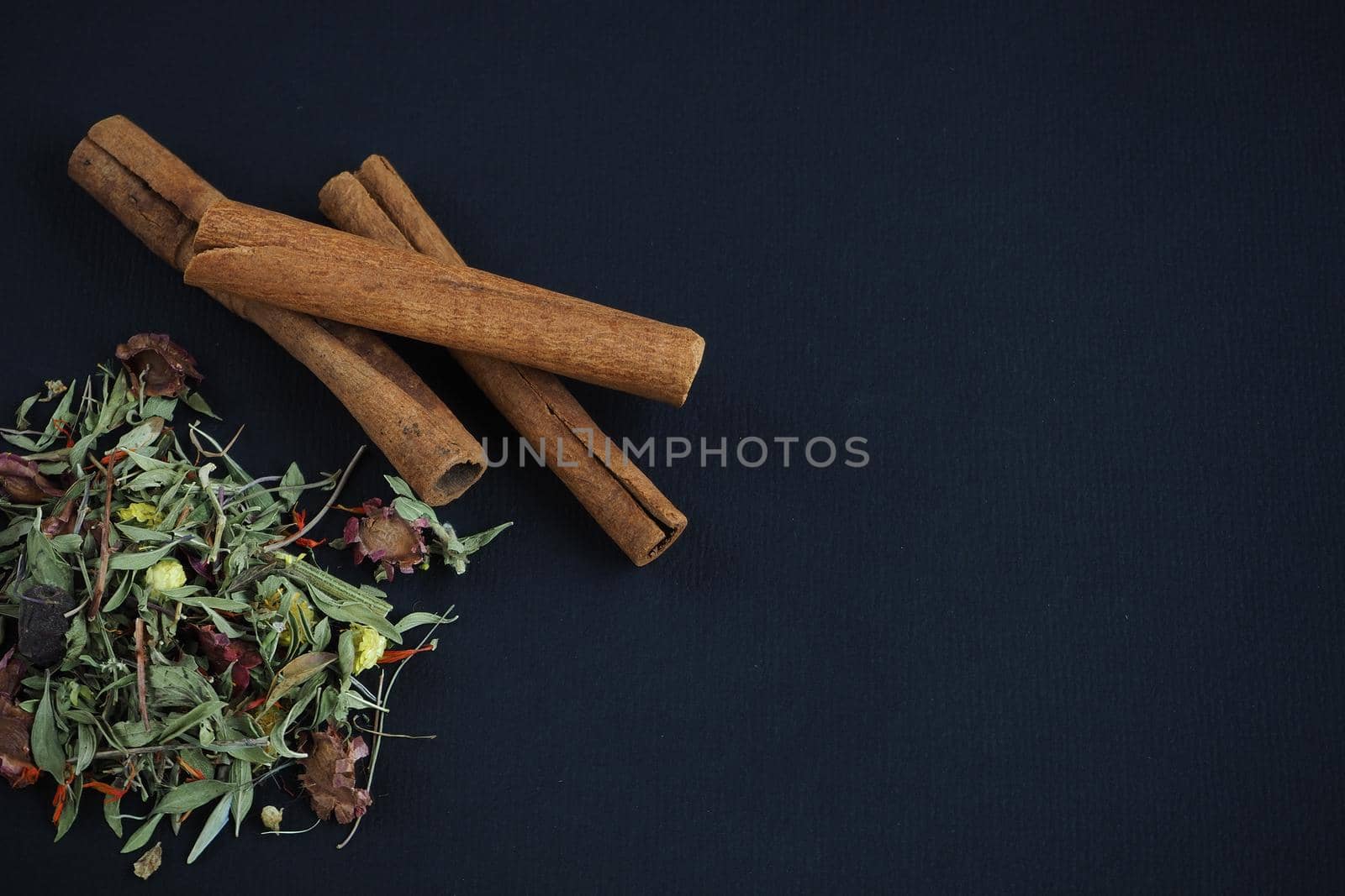 Dried cinnamon sticks and herbal tea on a black background. A quality image.