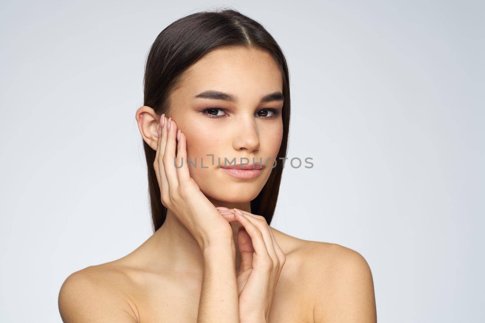 Woman with long hair bared shoulders clean skin body care light background. High quality photo