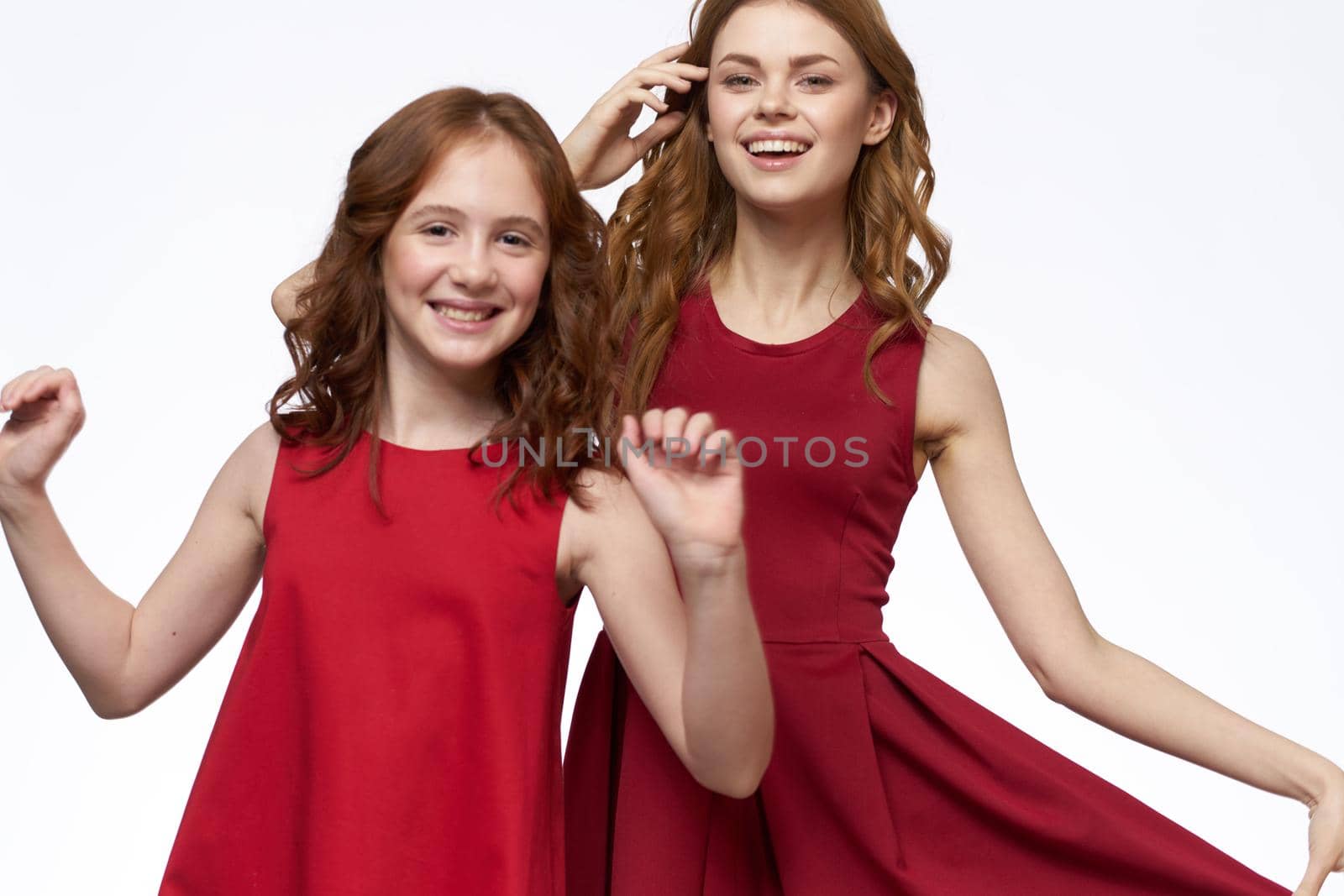 Cheerful mom and daughter next to red dresses hugs lifestyle light background smile. High quality photo