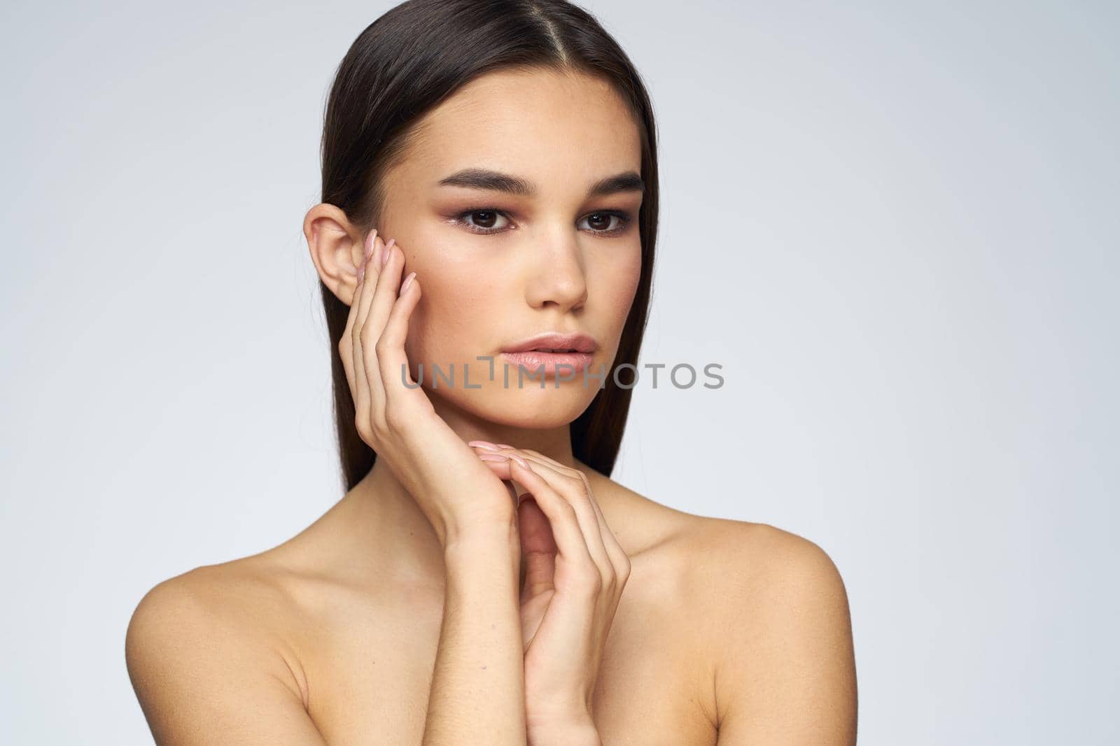 Woman with long hair bared shoulders clean skin body care light background. High quality photo