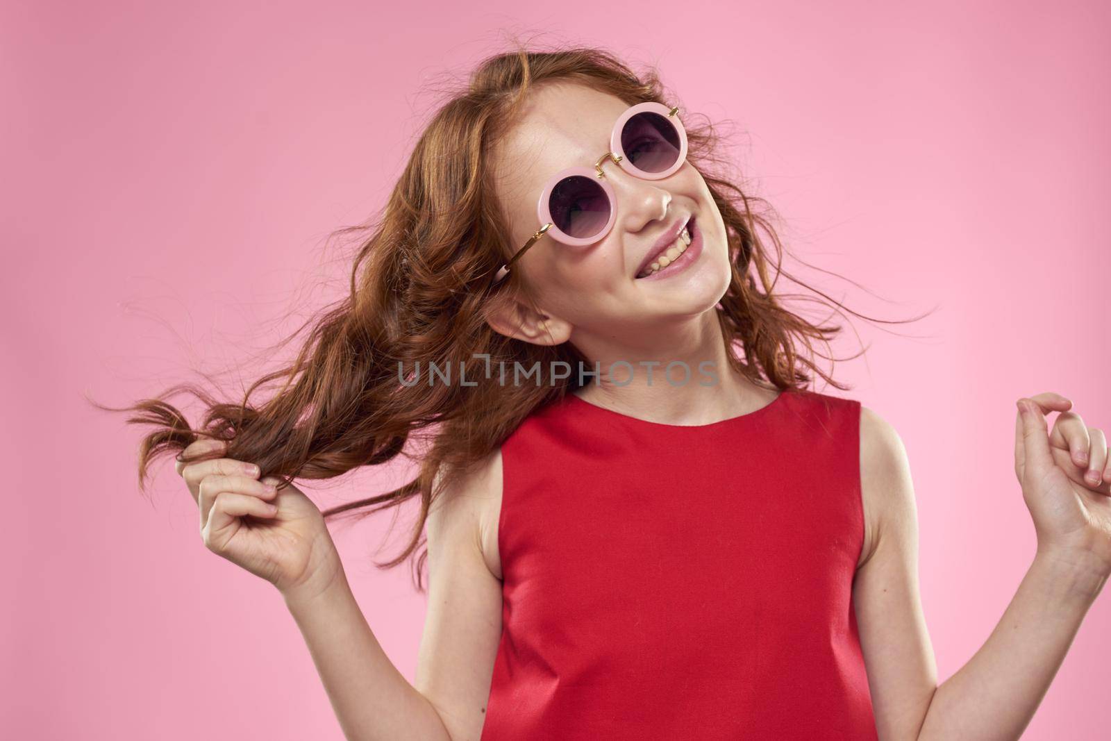 girl with curly hair sunglasses childhood joy pink background. High quality photo