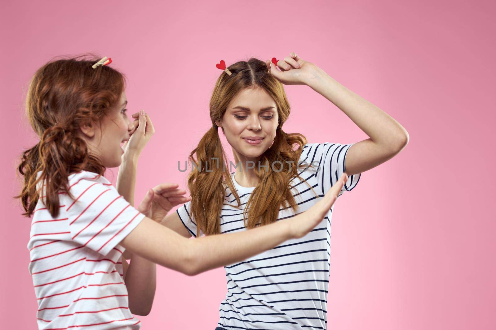 Woman and little girl on a pink background fun sisters friends family. High quality photo