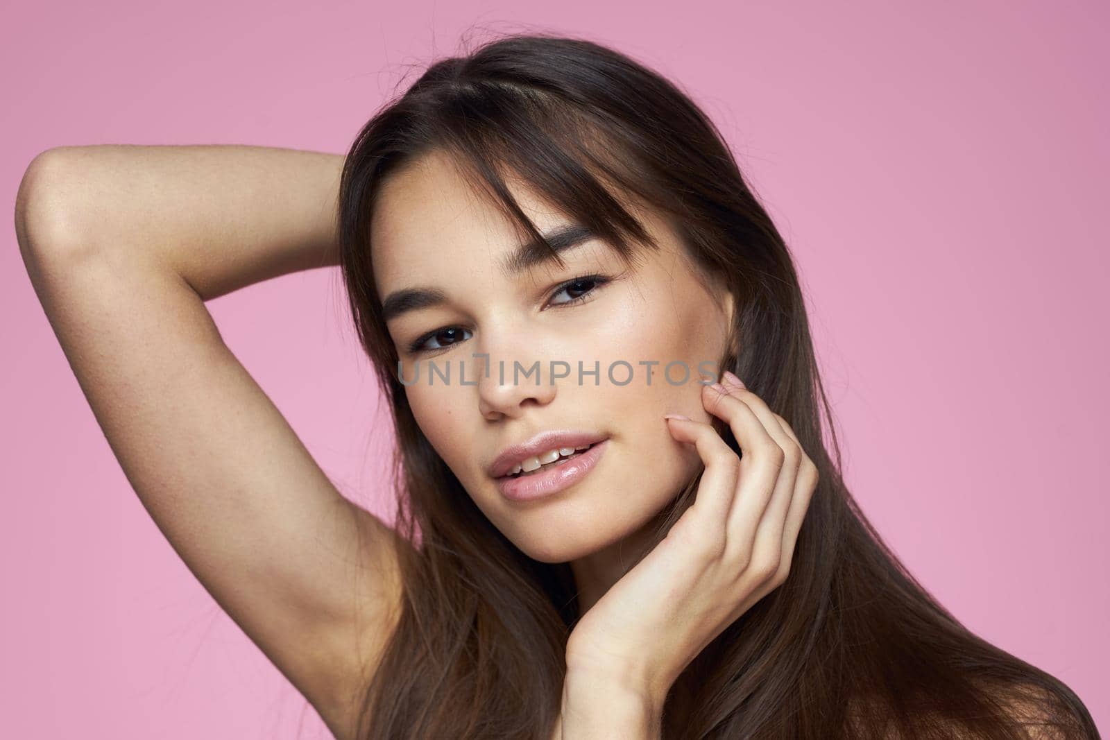 Pretty brunette naked shoulders clear skin pink background. High quality photo