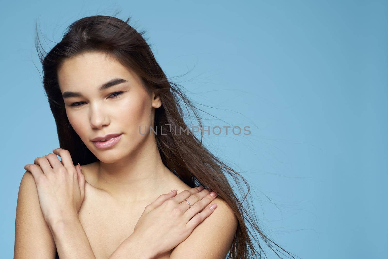 pretty brunette naked shoulders long hair skin care blue background. High quality photo