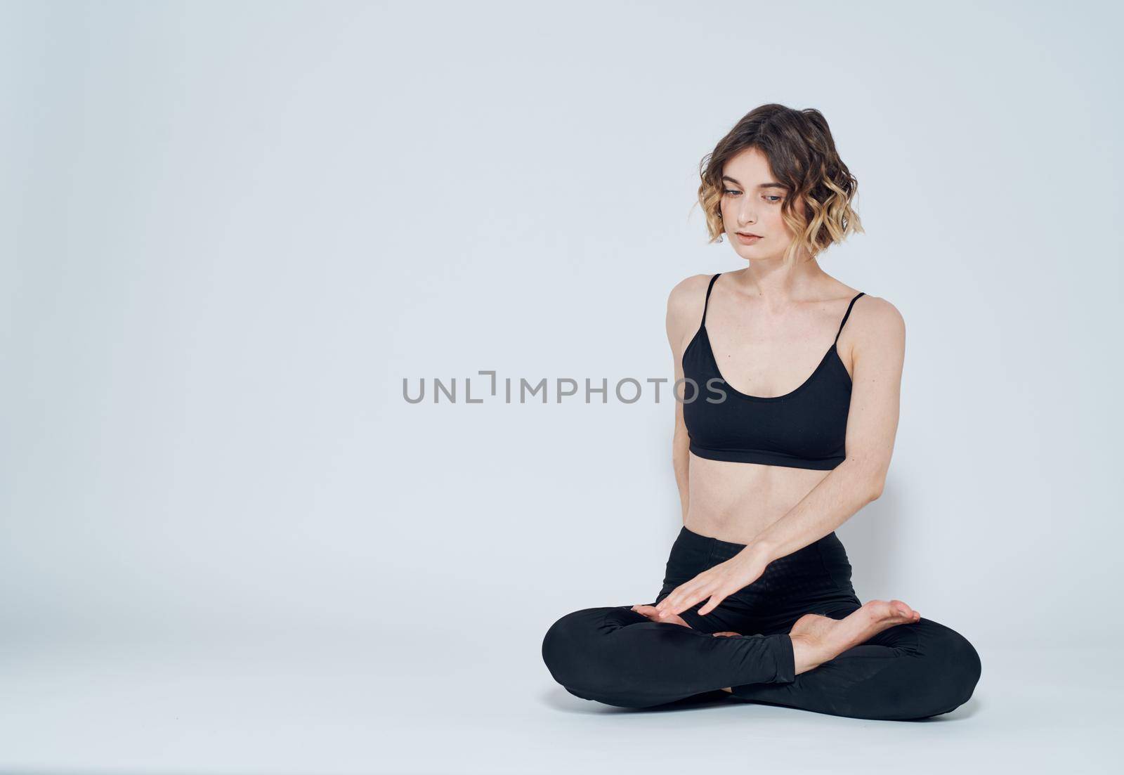 A woman in leggings sits cross-legged on the floor and turns to the sides by SHOTPRIME