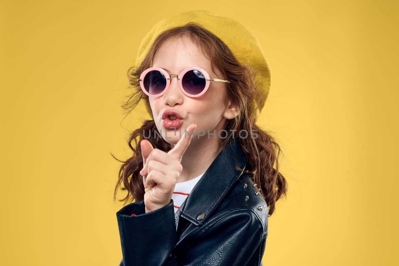 Girl in a yellow hat dark glasses fashionable clothes studio lifestyle childhood. High quality photo
