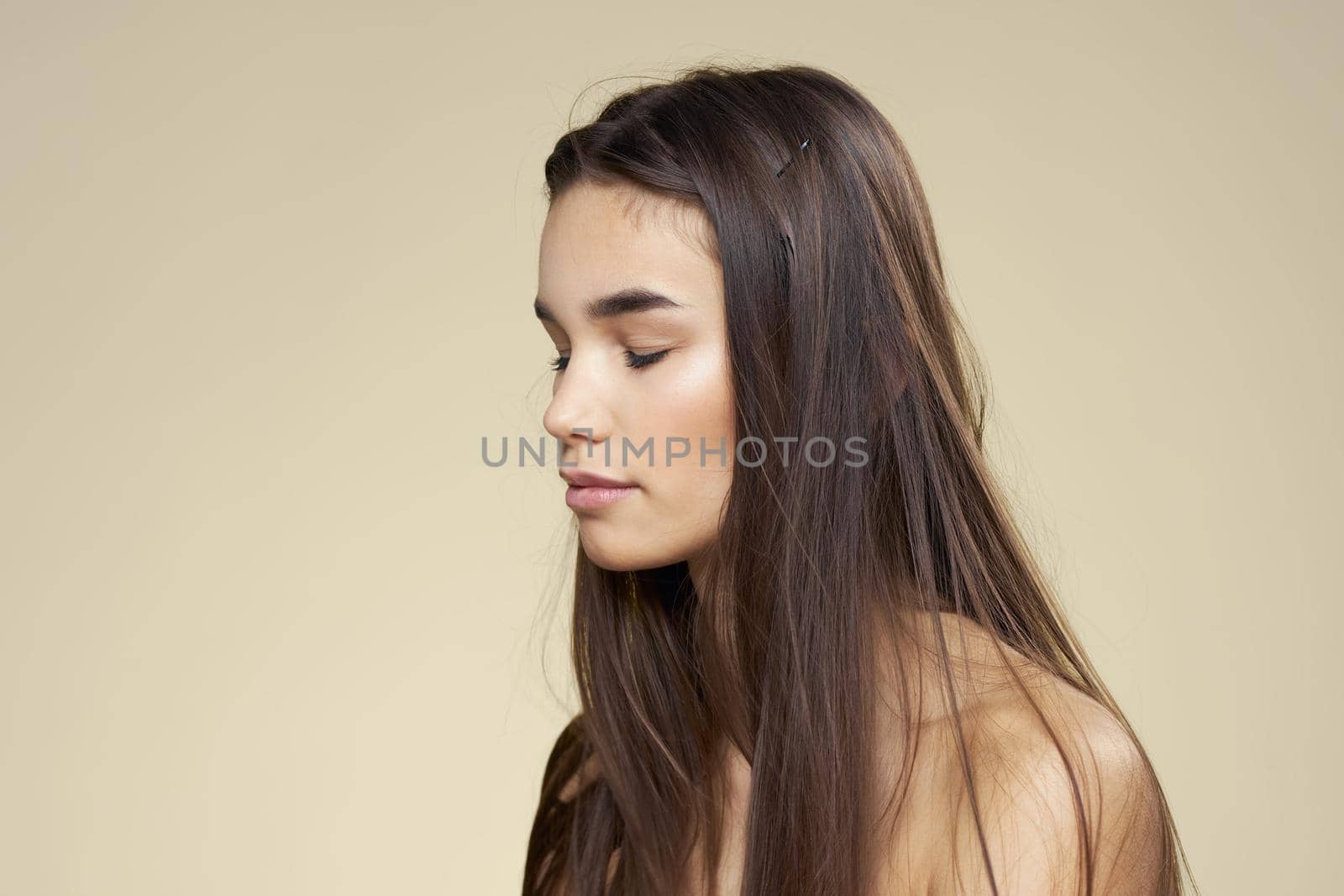 Pretty woman naked shoulders cosmetics clean skin hair care beige background. High quality photo