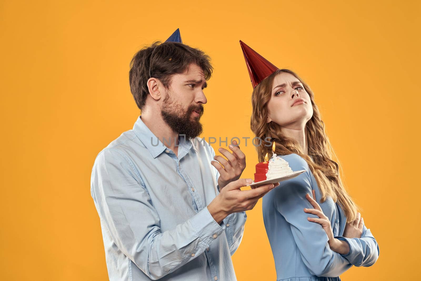 Birthday party man and woman in a cap with a cake on a yellow background cropped view. High quality photo