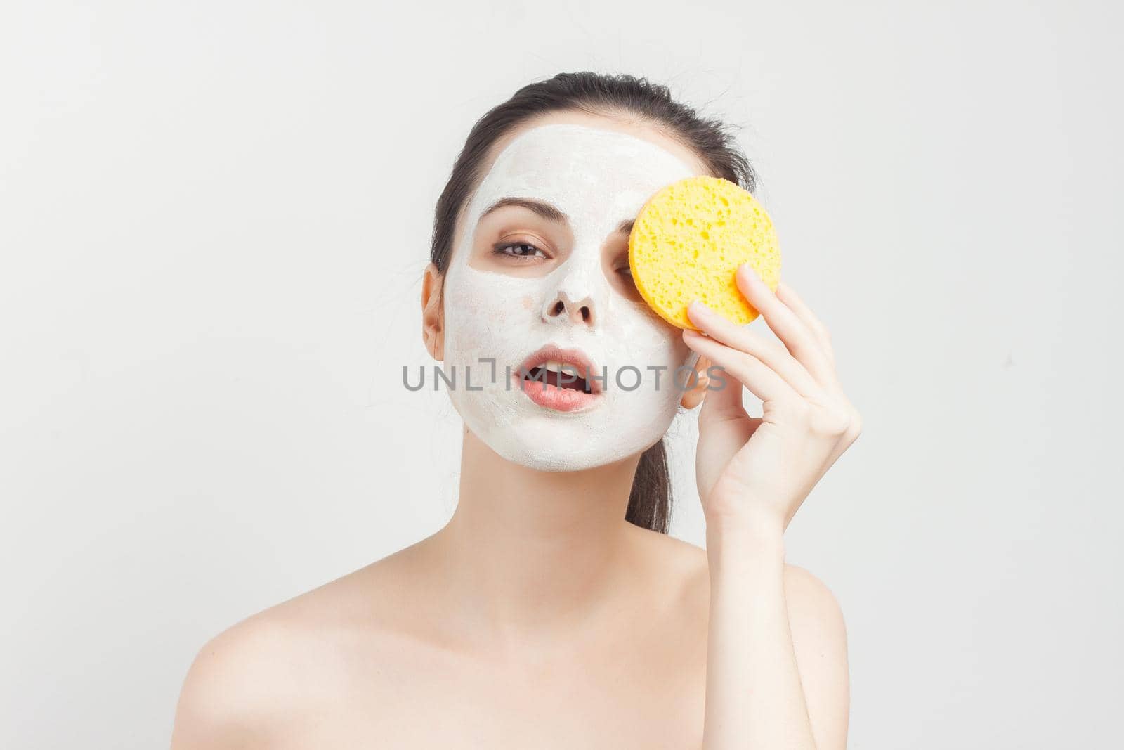 emotional brunette cream face mask bare shoulders cropped view clear skin. High quality photo