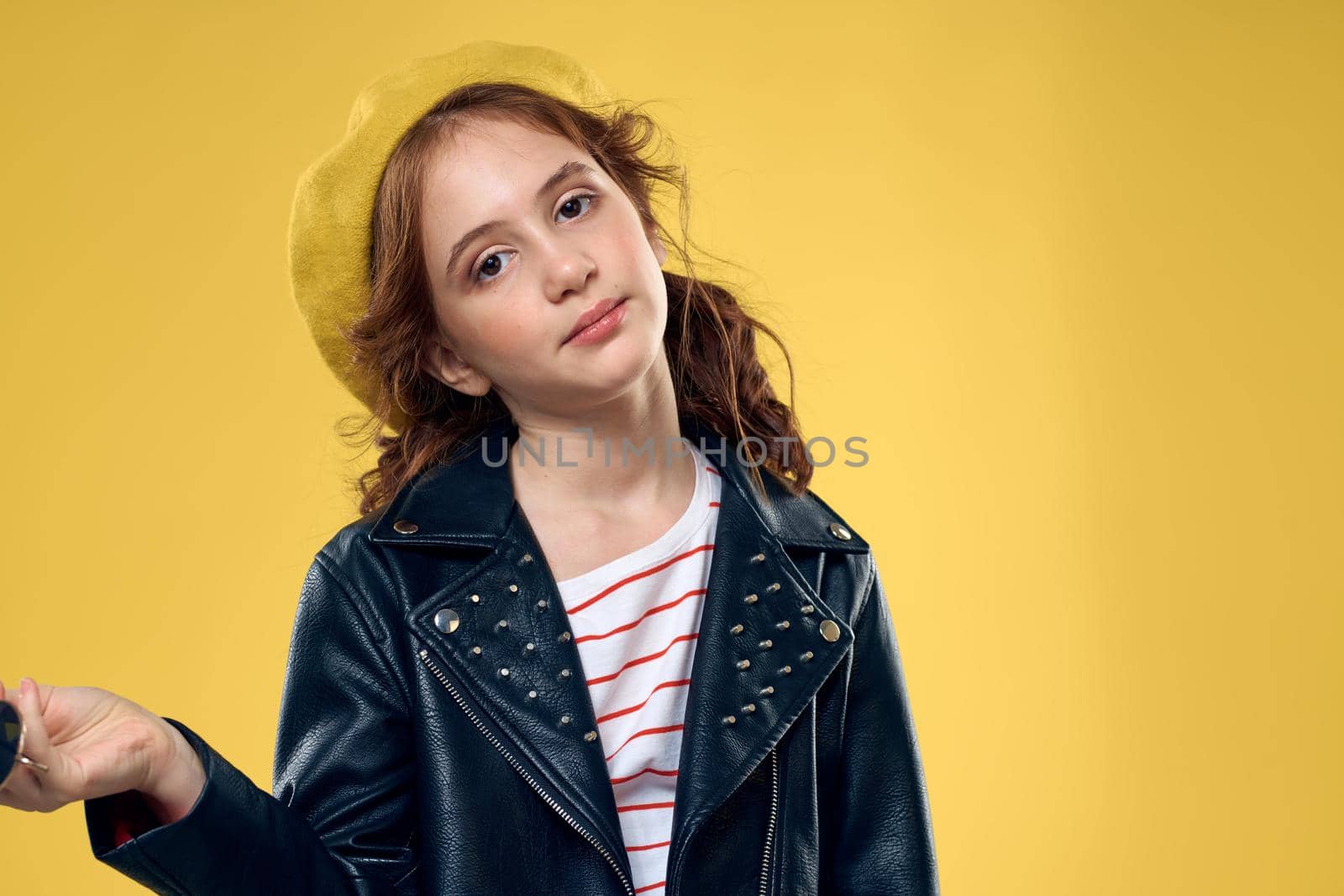 Cheerful little girl in sunglasses and hat lifestyle studio yellow background fashion. High quality photo