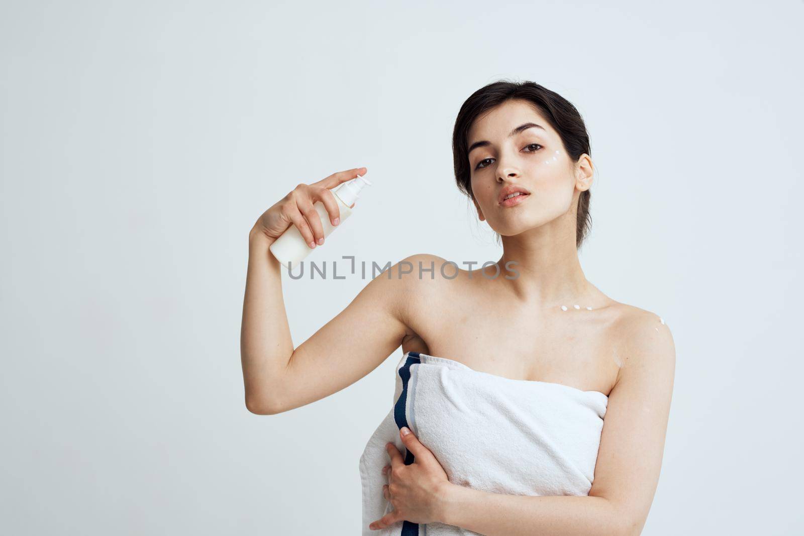 Pretty brunette white towel lotion for spa treatments. High quality photo