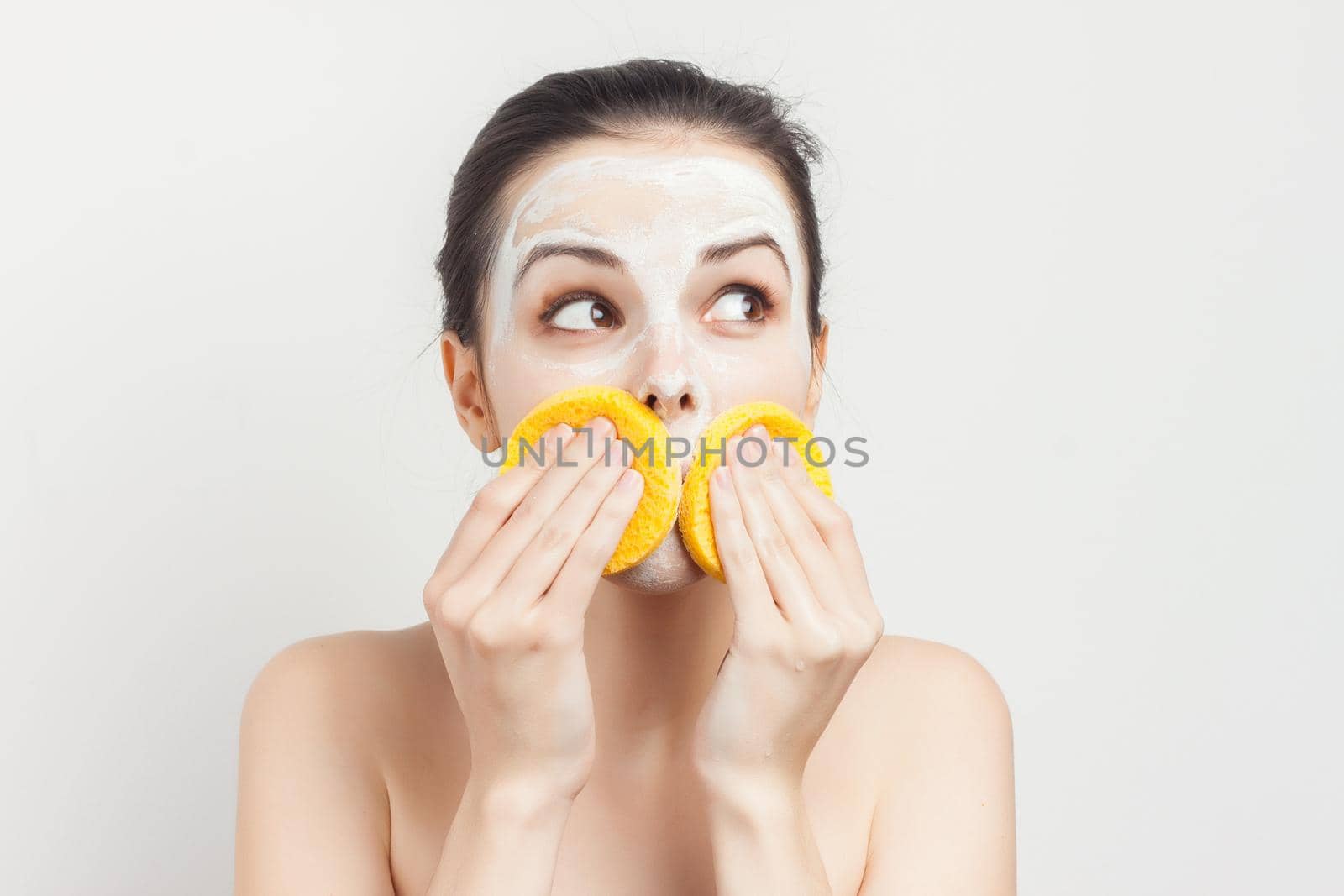 Cheerful brunette wipes face mask with sponges cropped view. High quality photo