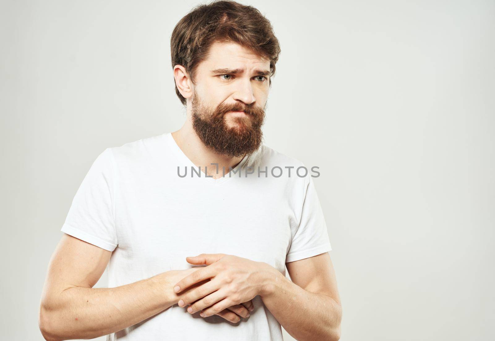 Guy in a white T-shirt on a light background emotions sad face cropped view. High quality photo
