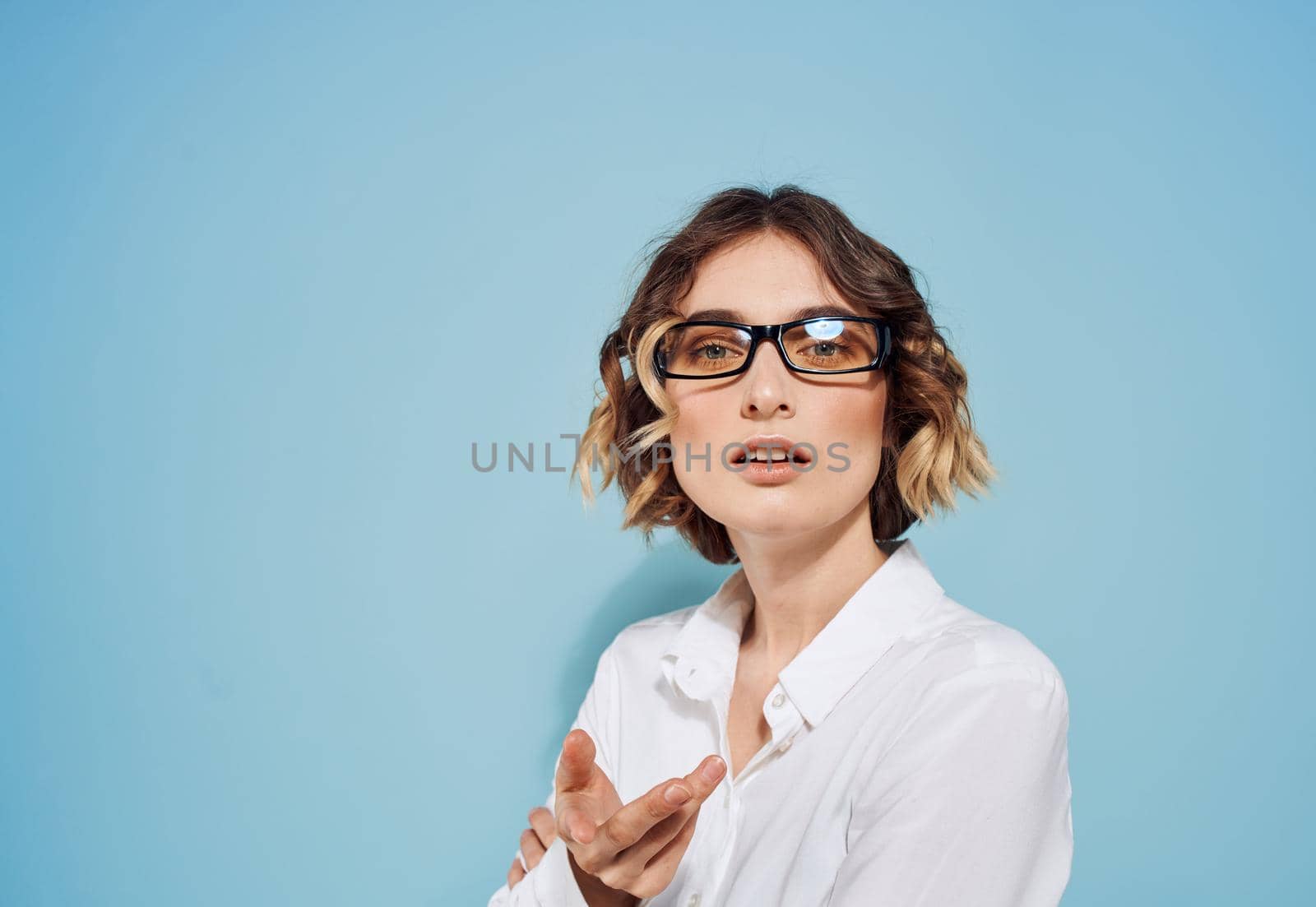 Beautiful lady with short hair in a white shirt on a blue background and glasses. High quality photo