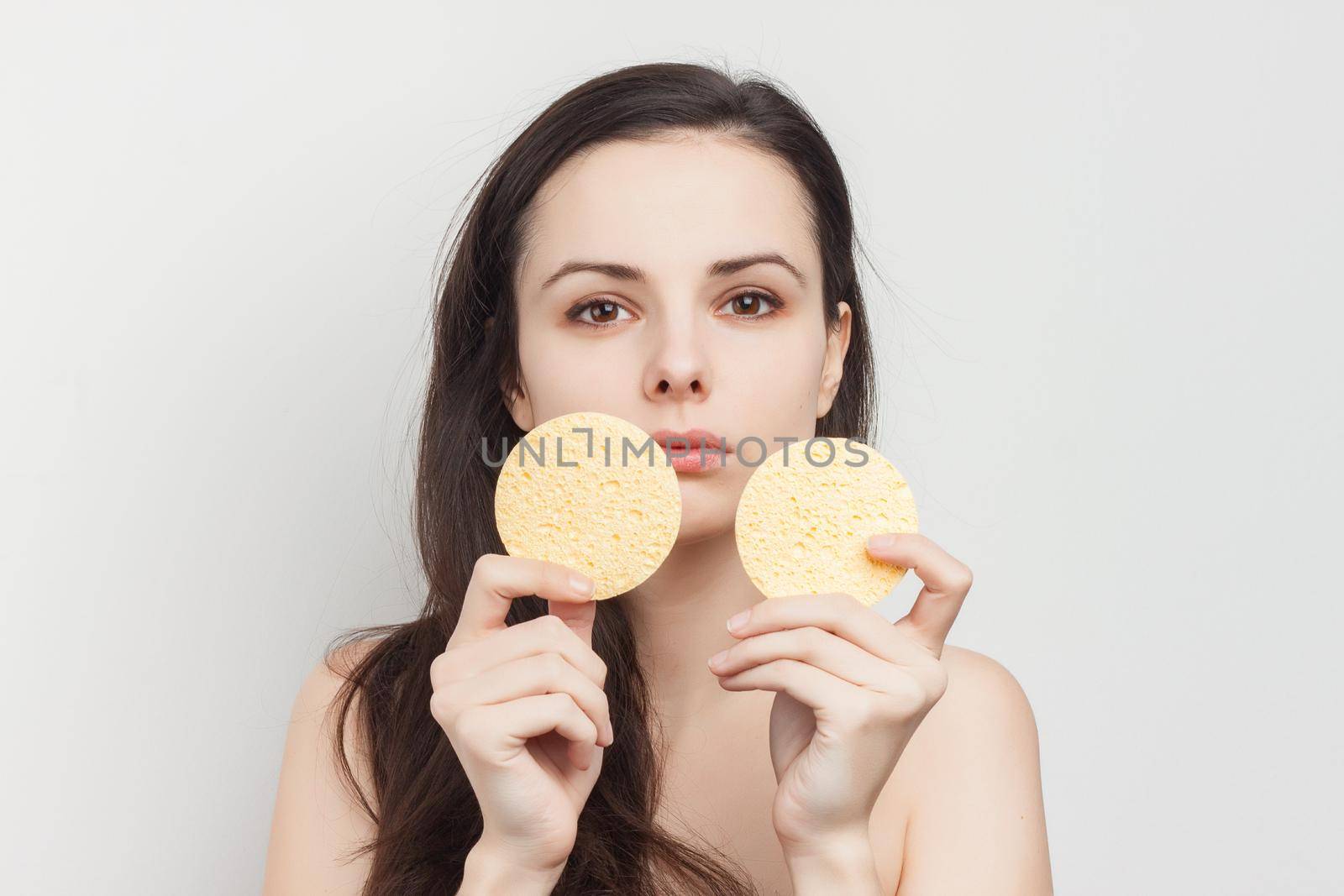 pretty brunette naked shoulders wipes her face but clean skin with a sponge by SHOTPRIME