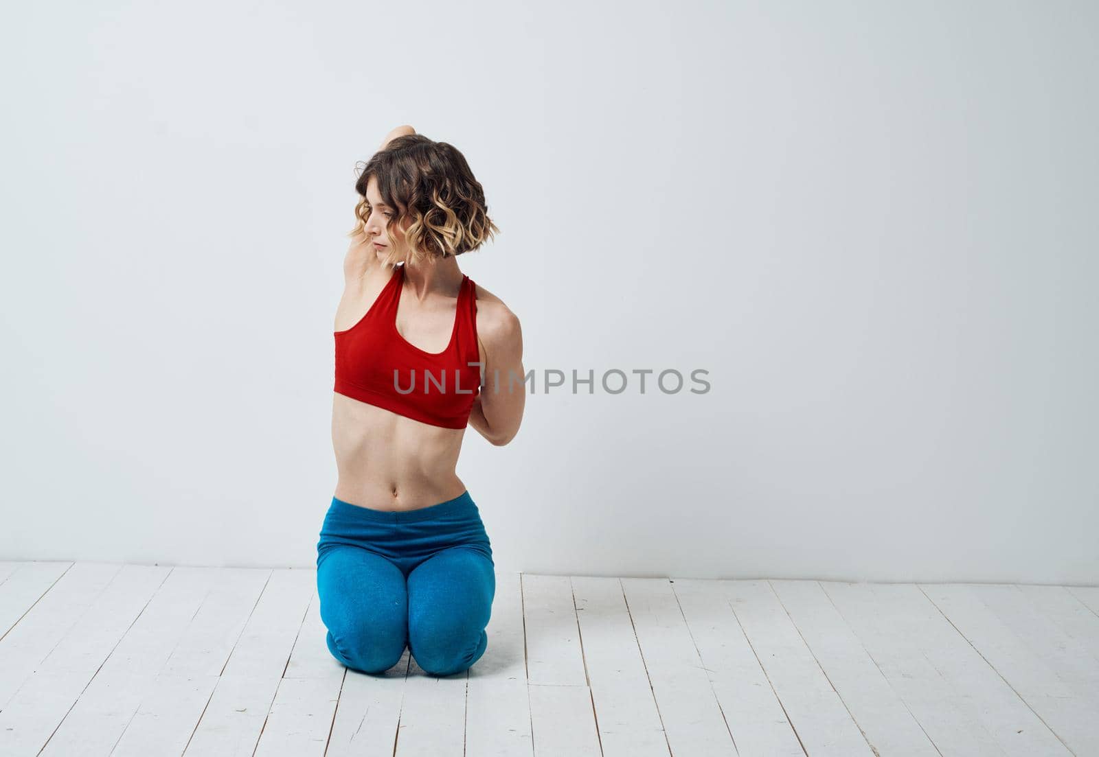 A woman in sportswear is doing yoga in a bright room and gesticulating with her hands by SHOTPRIME