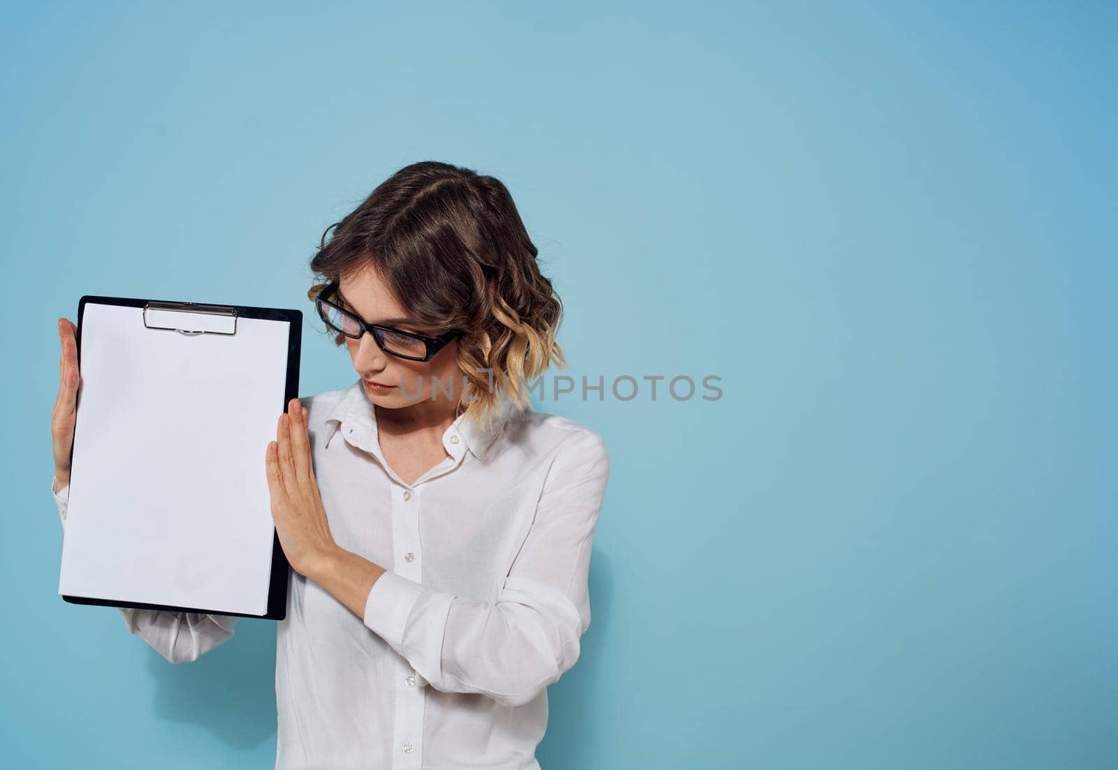 Business woman with a folder and a white sheet of paper on a blue background glasses on her face. High quality photo