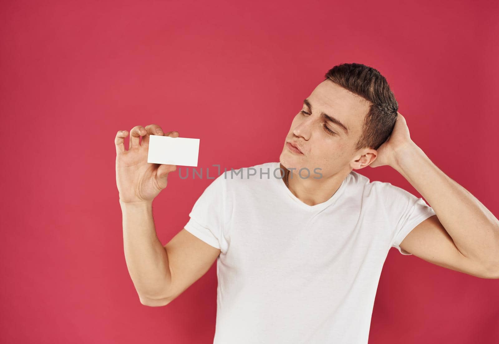Worker man with credit card on red background and white t-shirt cropped view. High quality photo