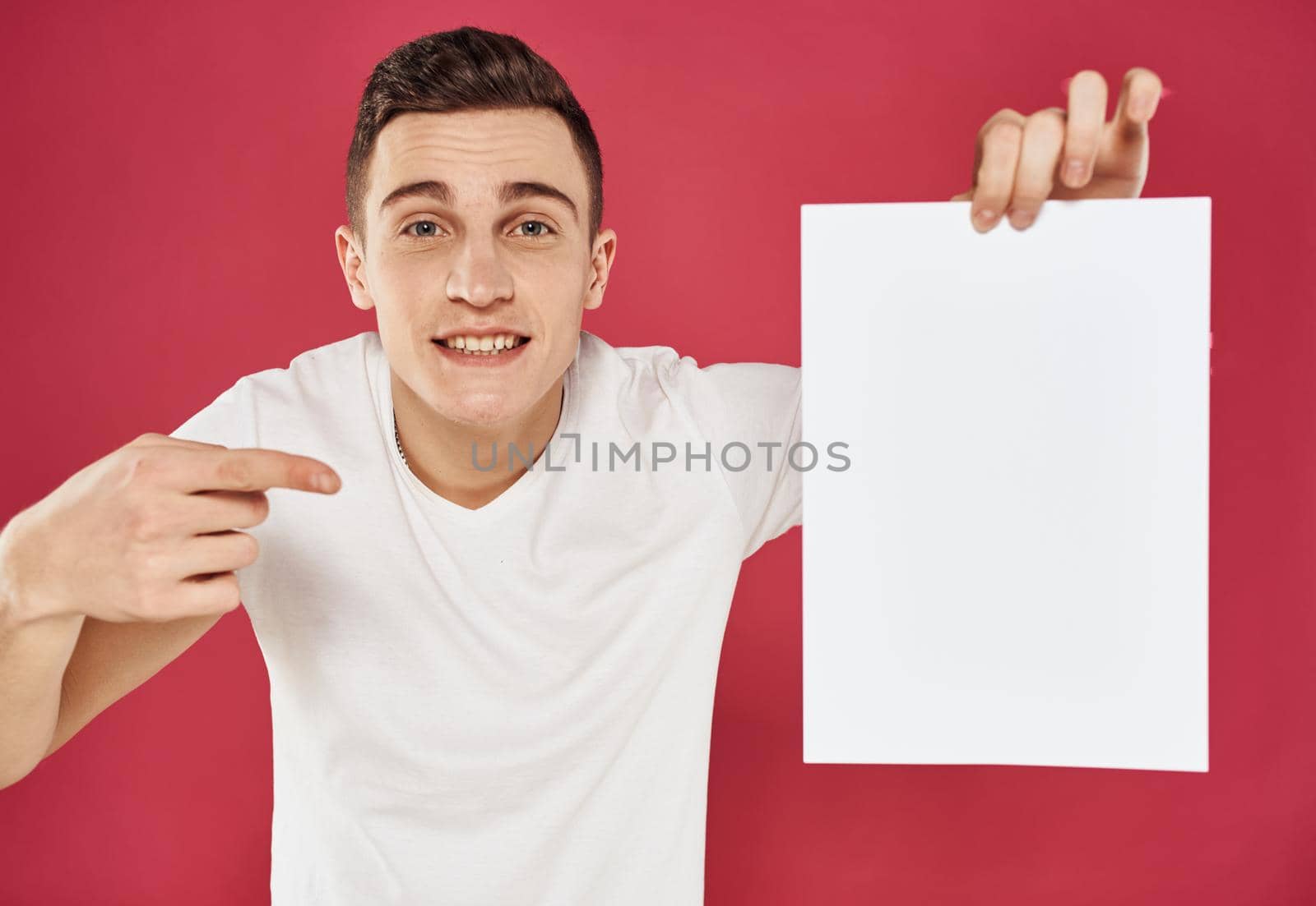 Man with a vertical sheet of paper on a red advertising background. High quality photo