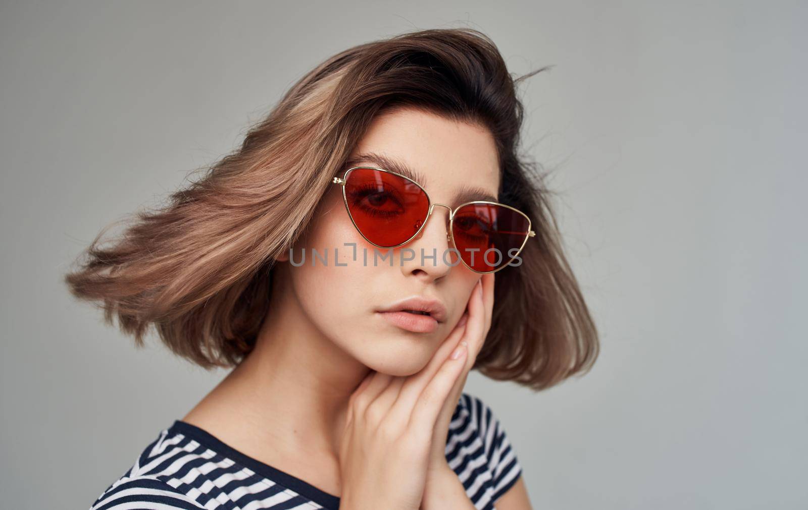 romantic woman in striped t-shirt portrait on gray background and fashionable glasses on face. High quality photo