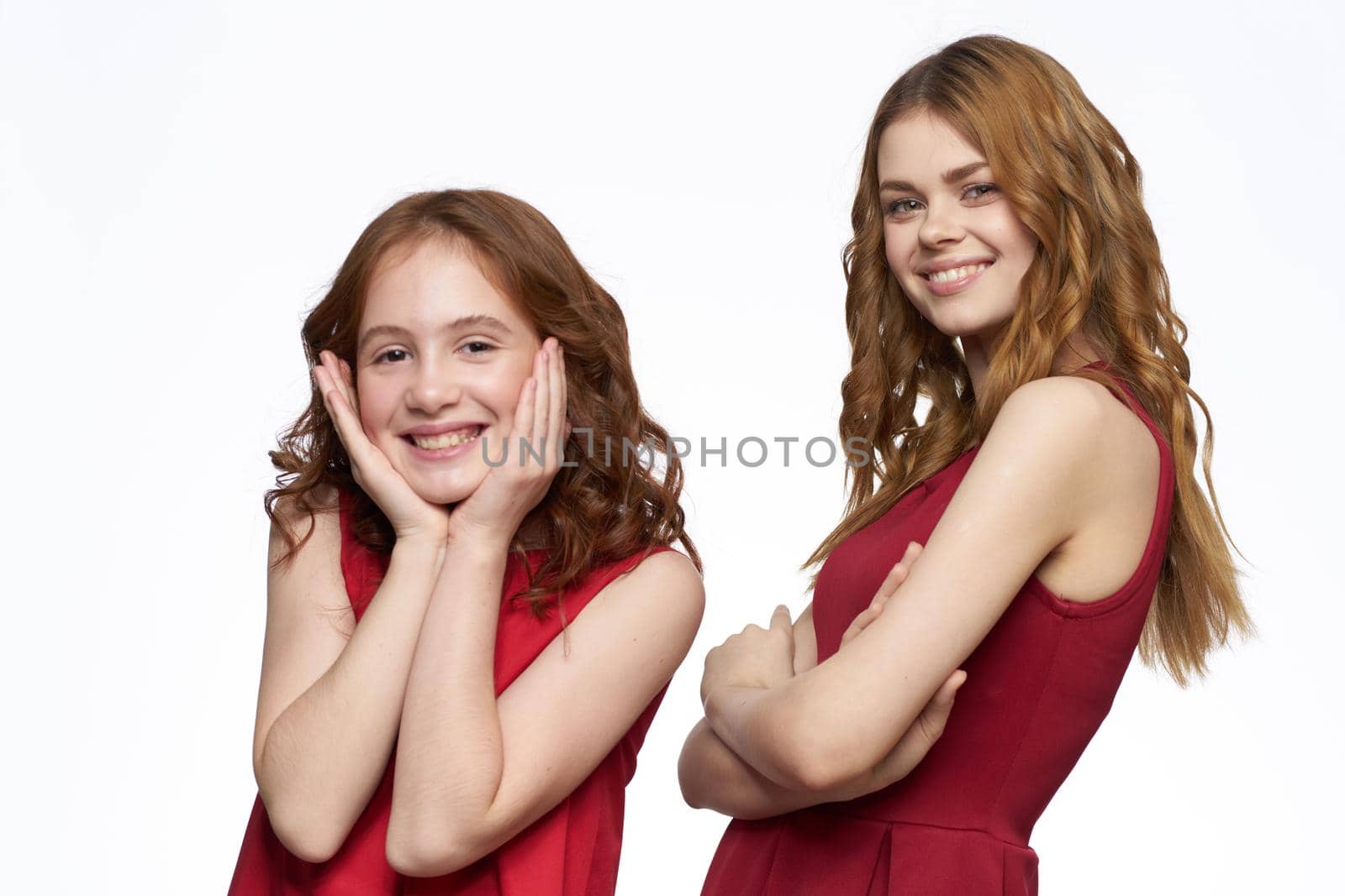 Cheerful mom and daughter in red dresses socializing light background by SHOTPRIME