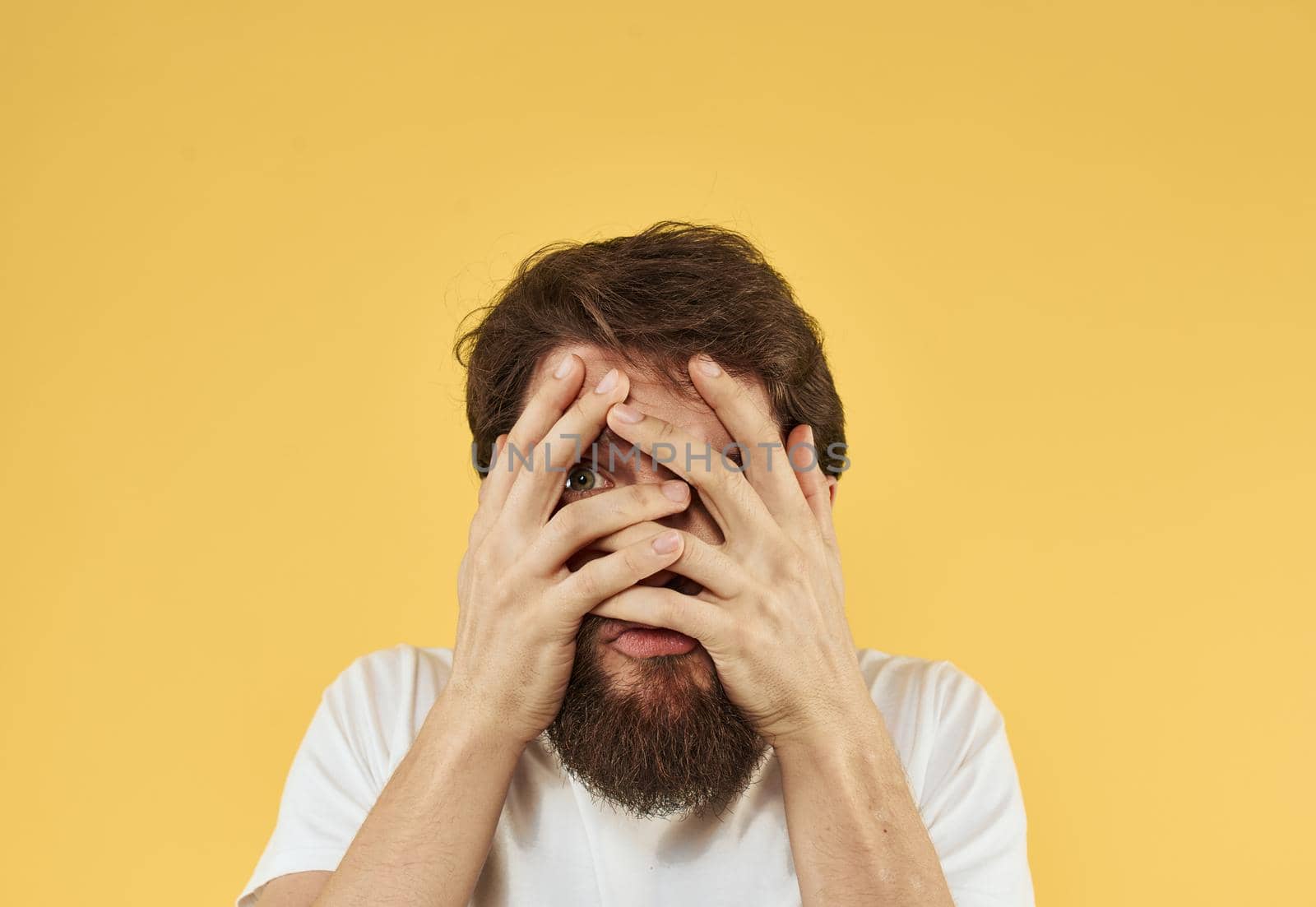 Upset man holds his hands near his face on a yellow background by SHOTPRIME