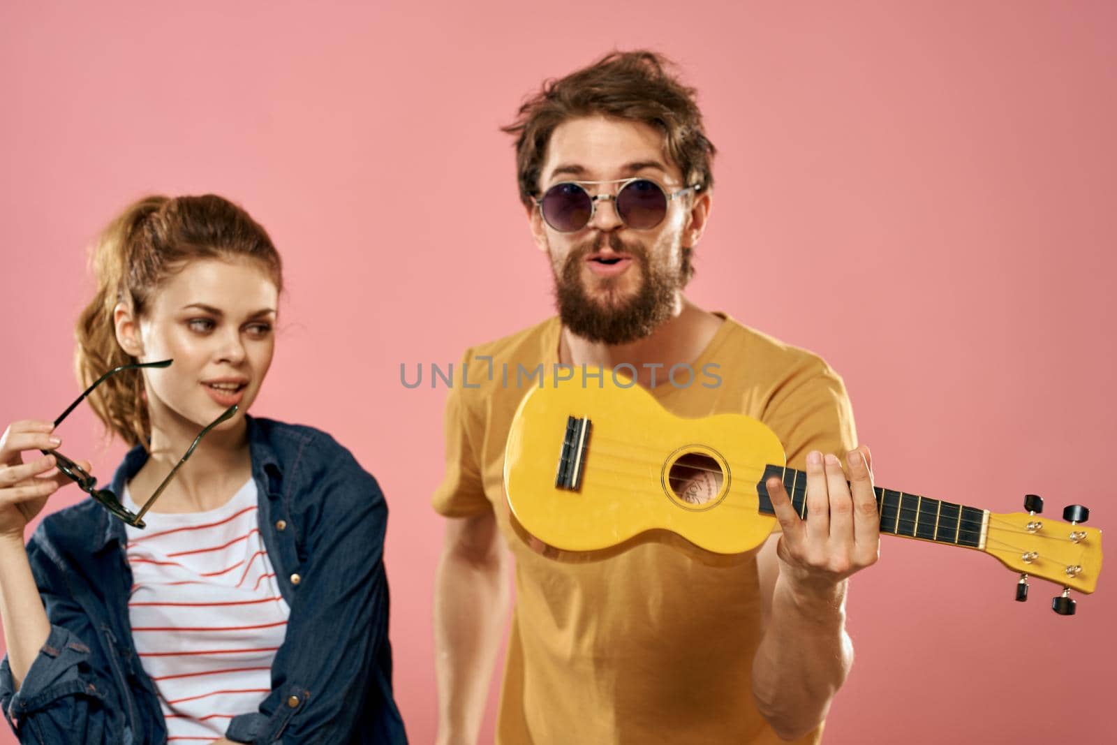 man and woman ukulele fun lifestyle pink background fashion. High quality photo