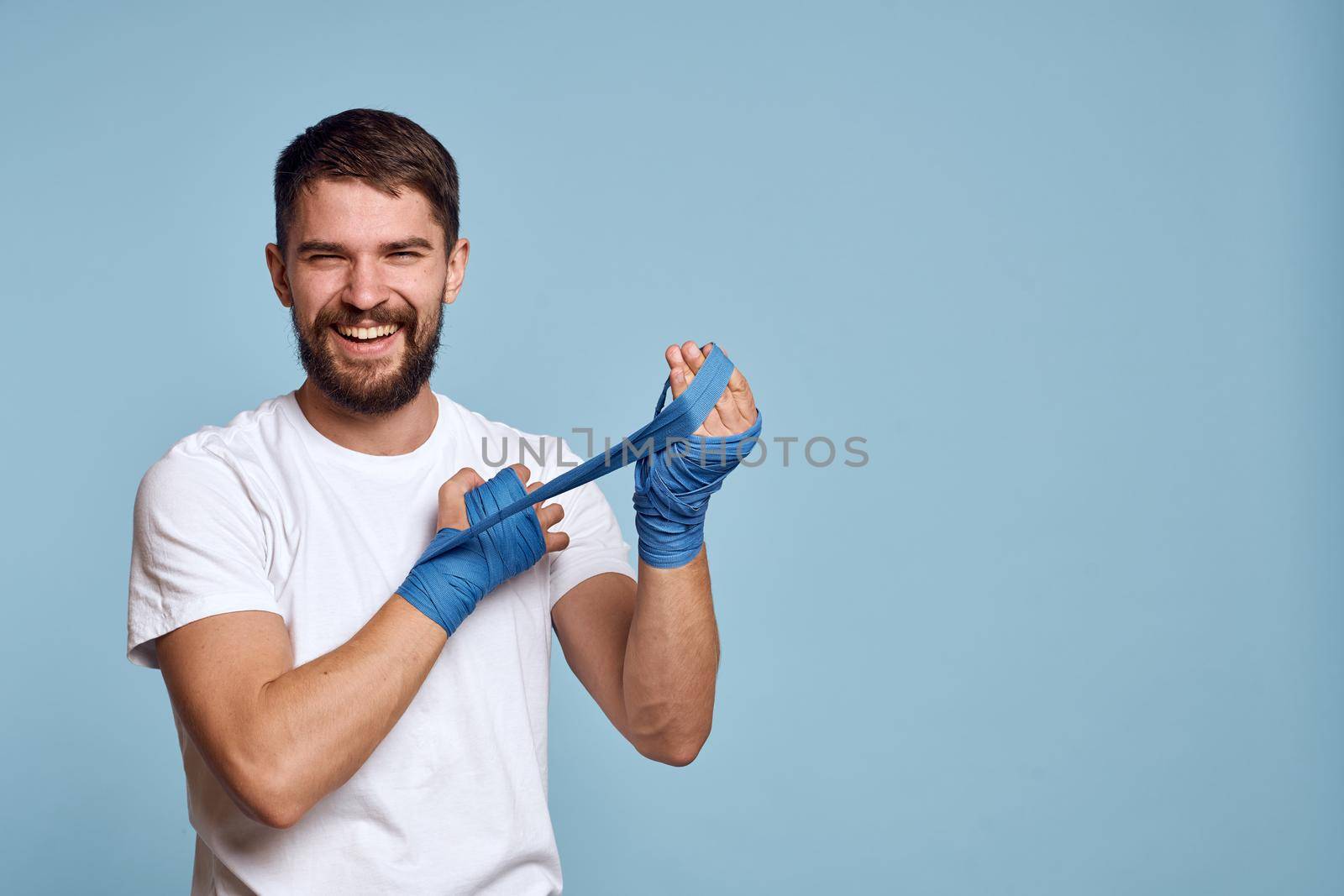 Man in white t-shirt sport boxing bandages energy blue background by SHOTPRIME