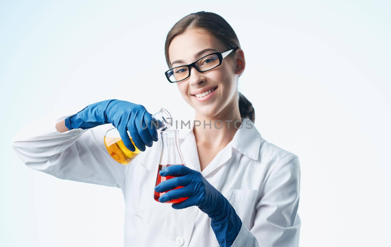 a nurse in a lab coat and blue gloves with a flask in her hand chemical element laboratory analyzes by SHOTPRIME