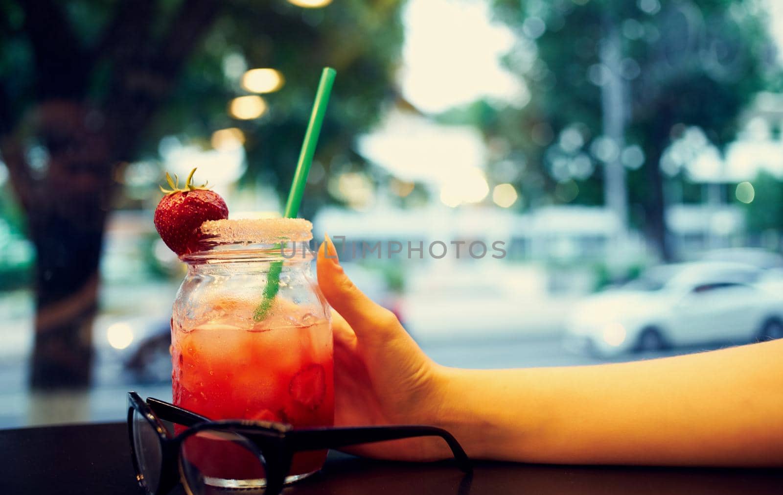 glass with a drink in a woman's hand and cafe by SHOTPRIME
