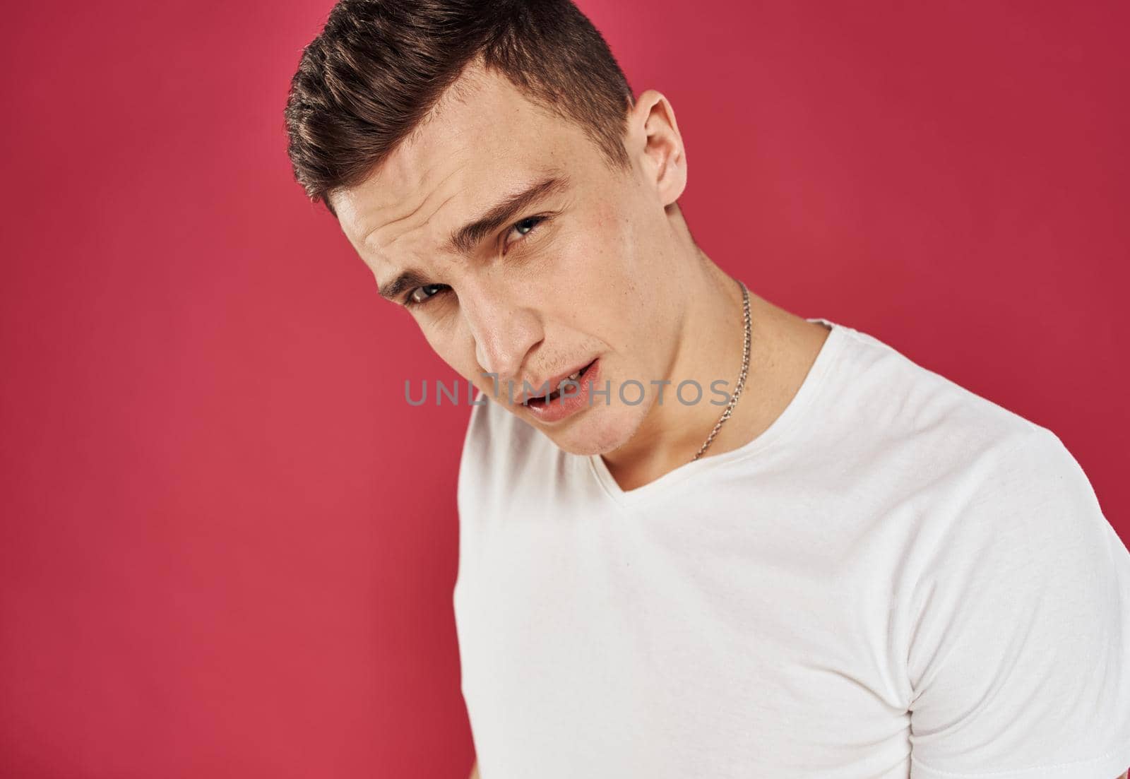 man in white t-shirt close-up red background dissatisfaction. High quality photo