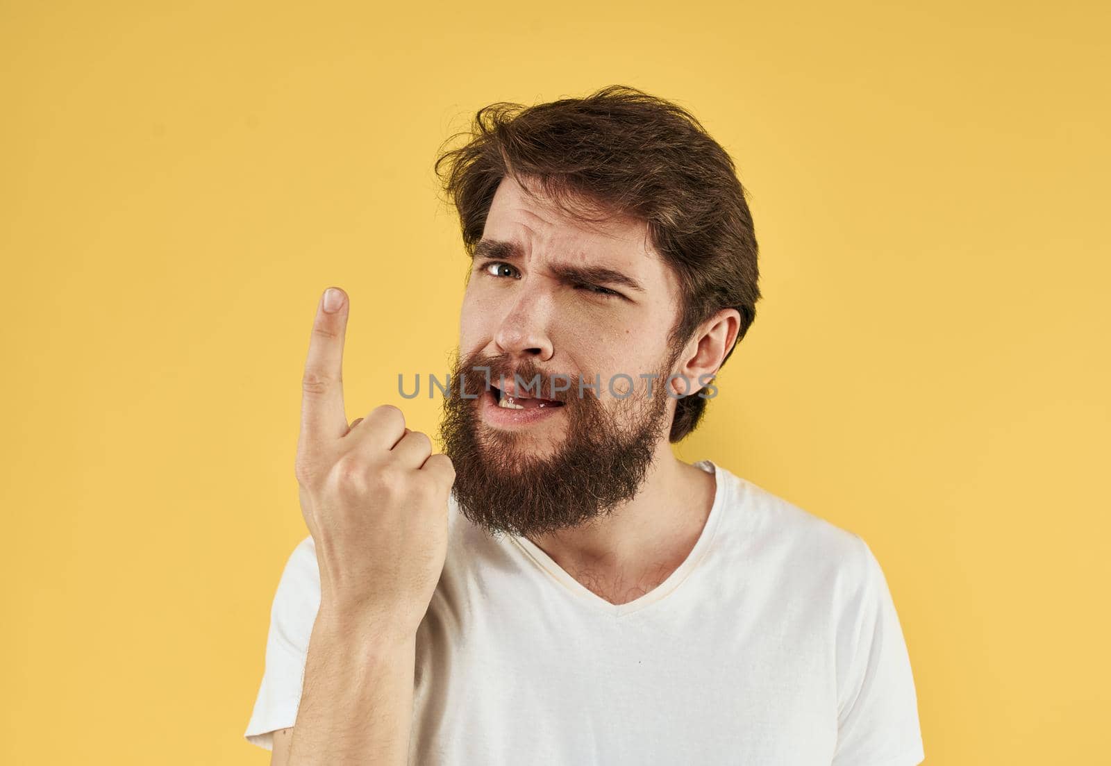 Brunette man gesturing with his hands on yellow background cropped view. High quality photo