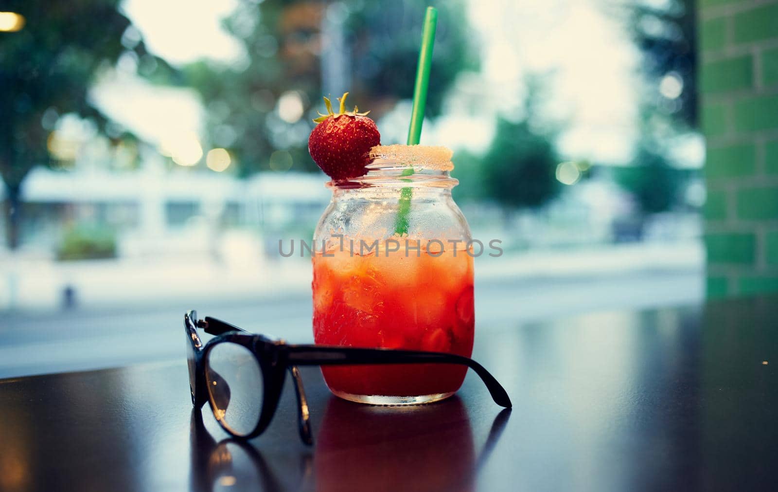 glass with a drink in a woman's hand and cafe by SHOTPRIME