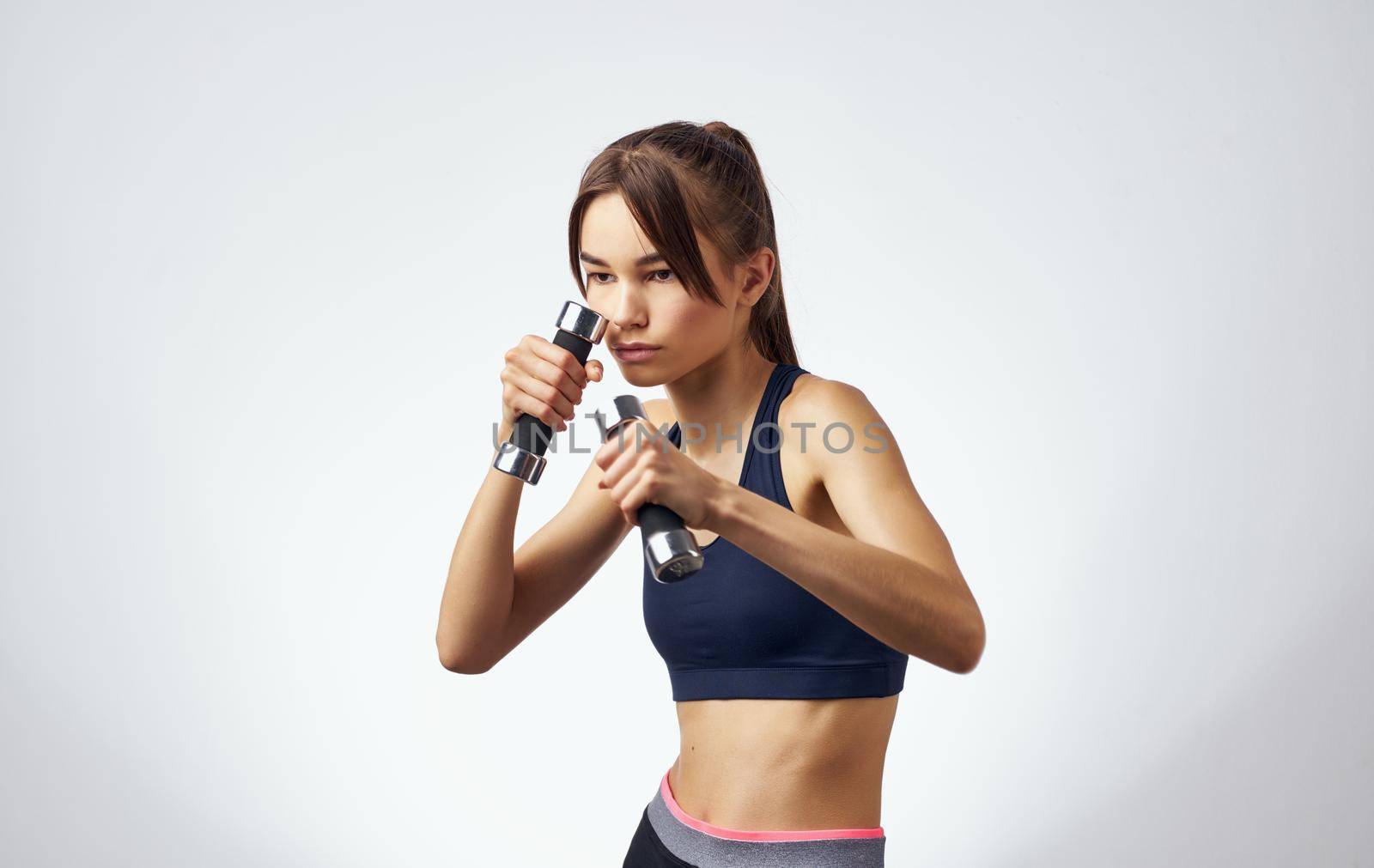 energetic sportswoman is engaged in active exercises on a light background and dumbbells towel fitness. High quality photo