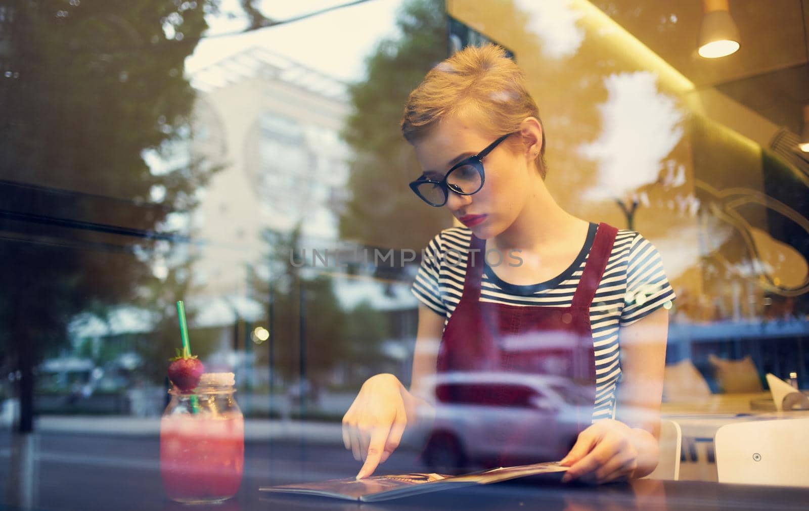 women in a sundress sitting in a cafe and looking at the street through the glass. High quality photo