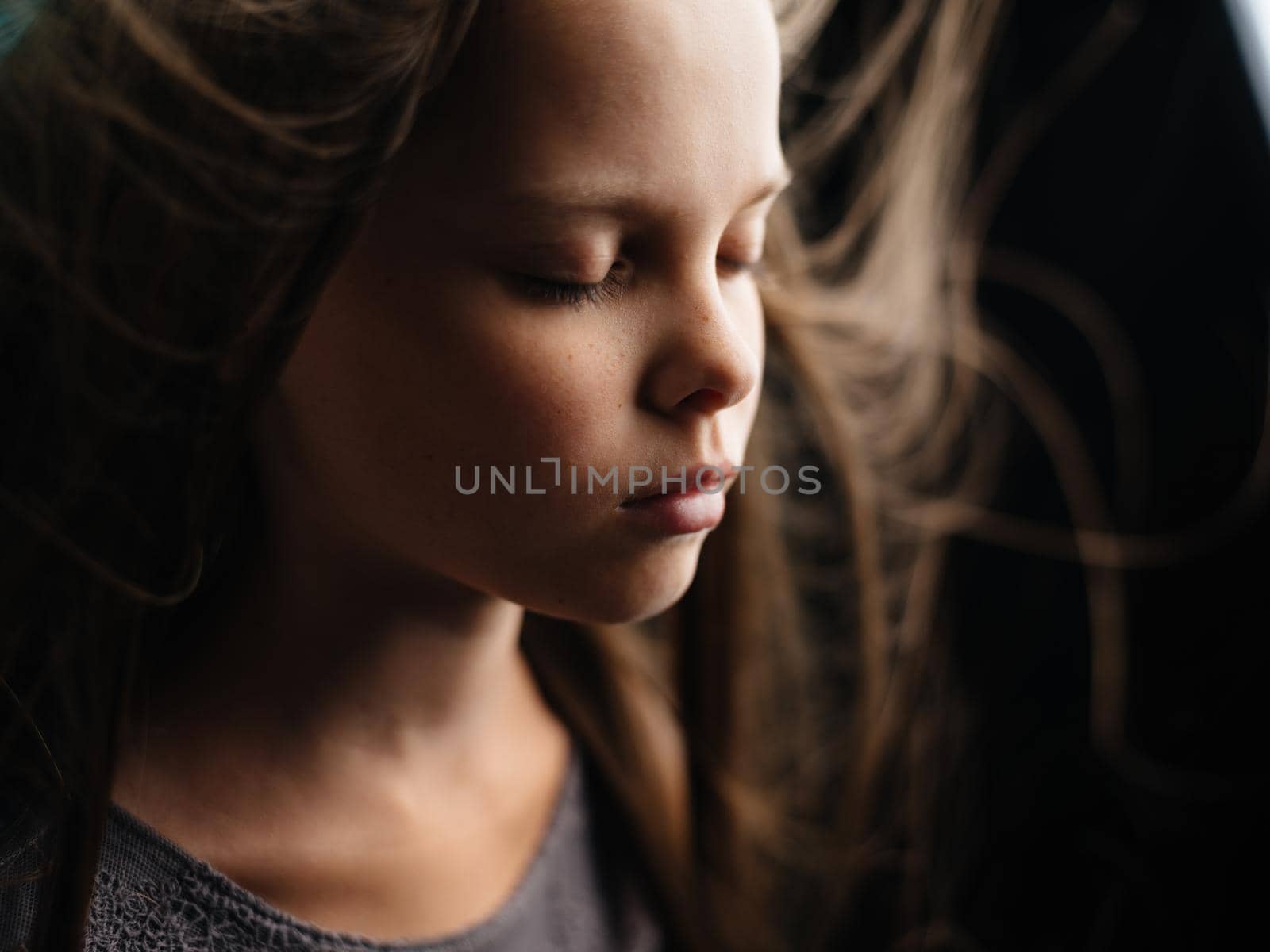 Portrait of a beautiful girl with closed eyes on a turquoise background and loose hair close-up cropped view. by SHOTPRIME