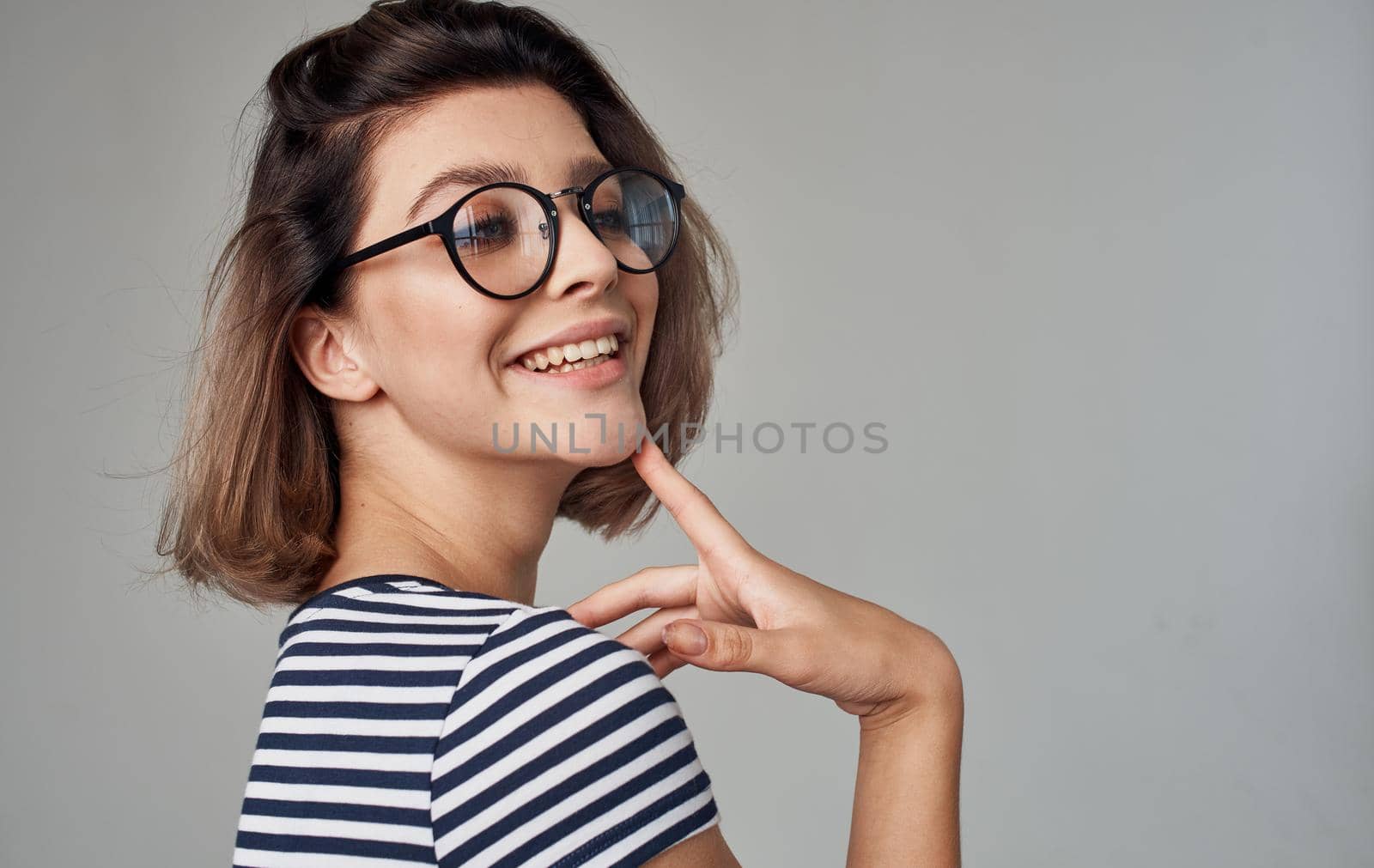 portrait of a happy blonde in a striped t-shirt and his glasses on a gray background. High quality photo