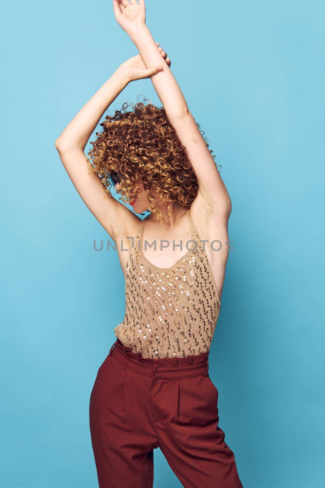 Attractive woman Curly hair hands over head movement fashionable clothes charm cropped view